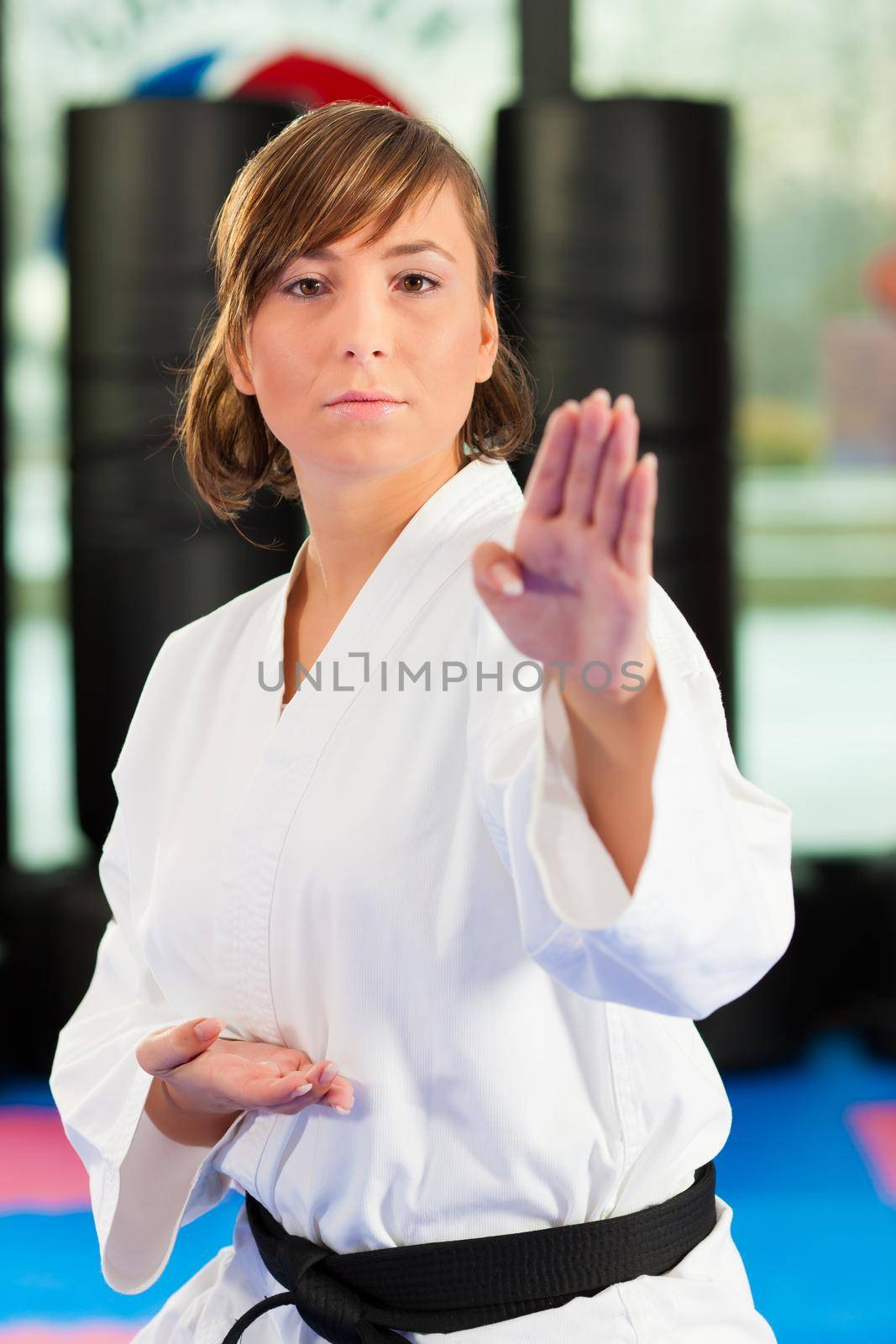 Woman in martial art training in a gym, she is wearing a black belt