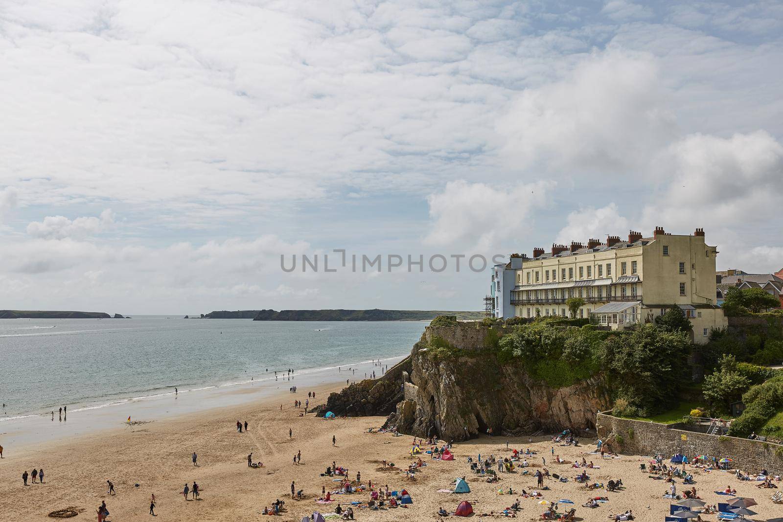 TENBY, WALES, UK - AUGUST 13, 2017: People enjoying the harbour and Castle at Tenby, an ancient walled town; now a tourist destination in the county of Pembrokeshire, south Wales, UK.