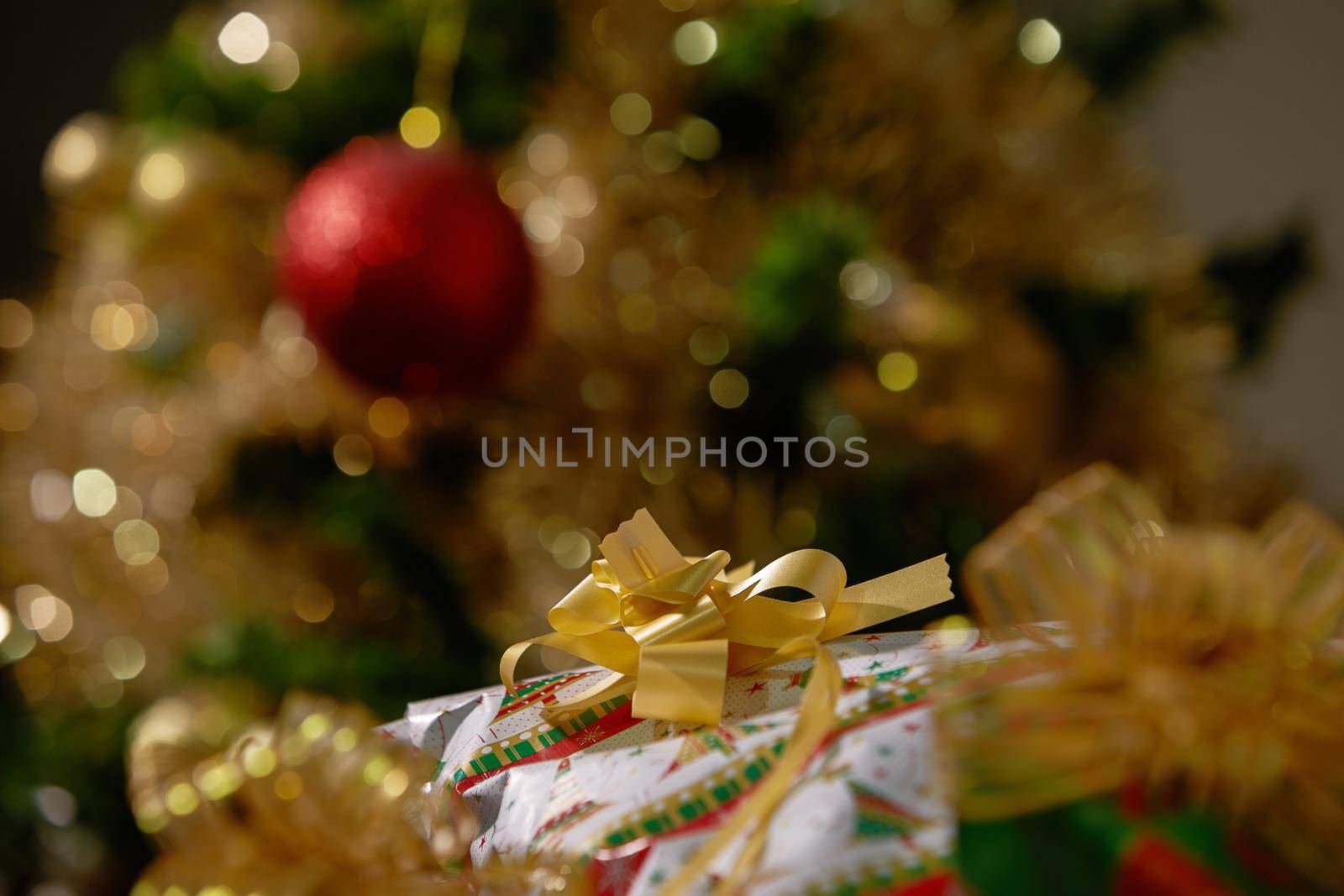Stacks of Christmas Presents Under a Christmas Tree with Defocused Lights.