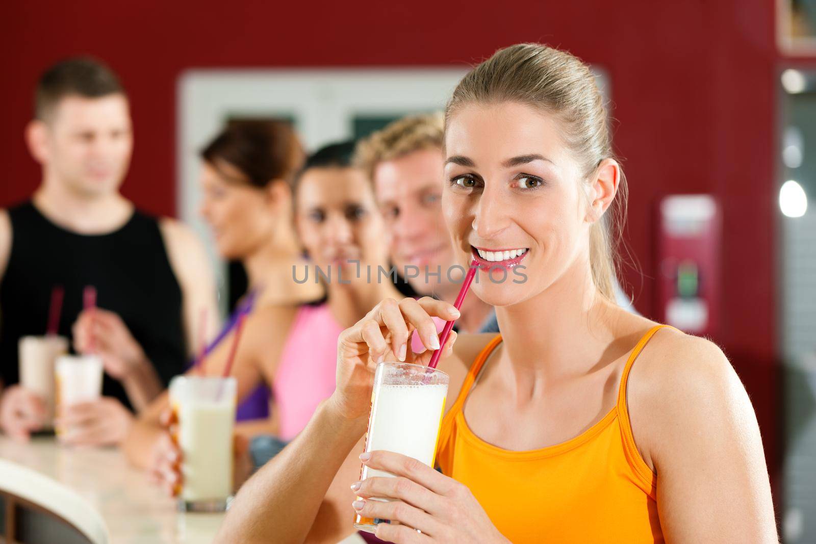 People drinking protein shake after workout in gym or fitness club