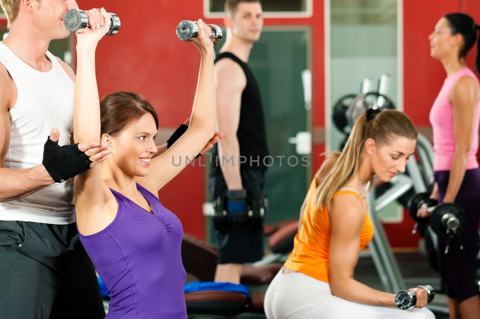 People in gym exercising with weights by Kzenon