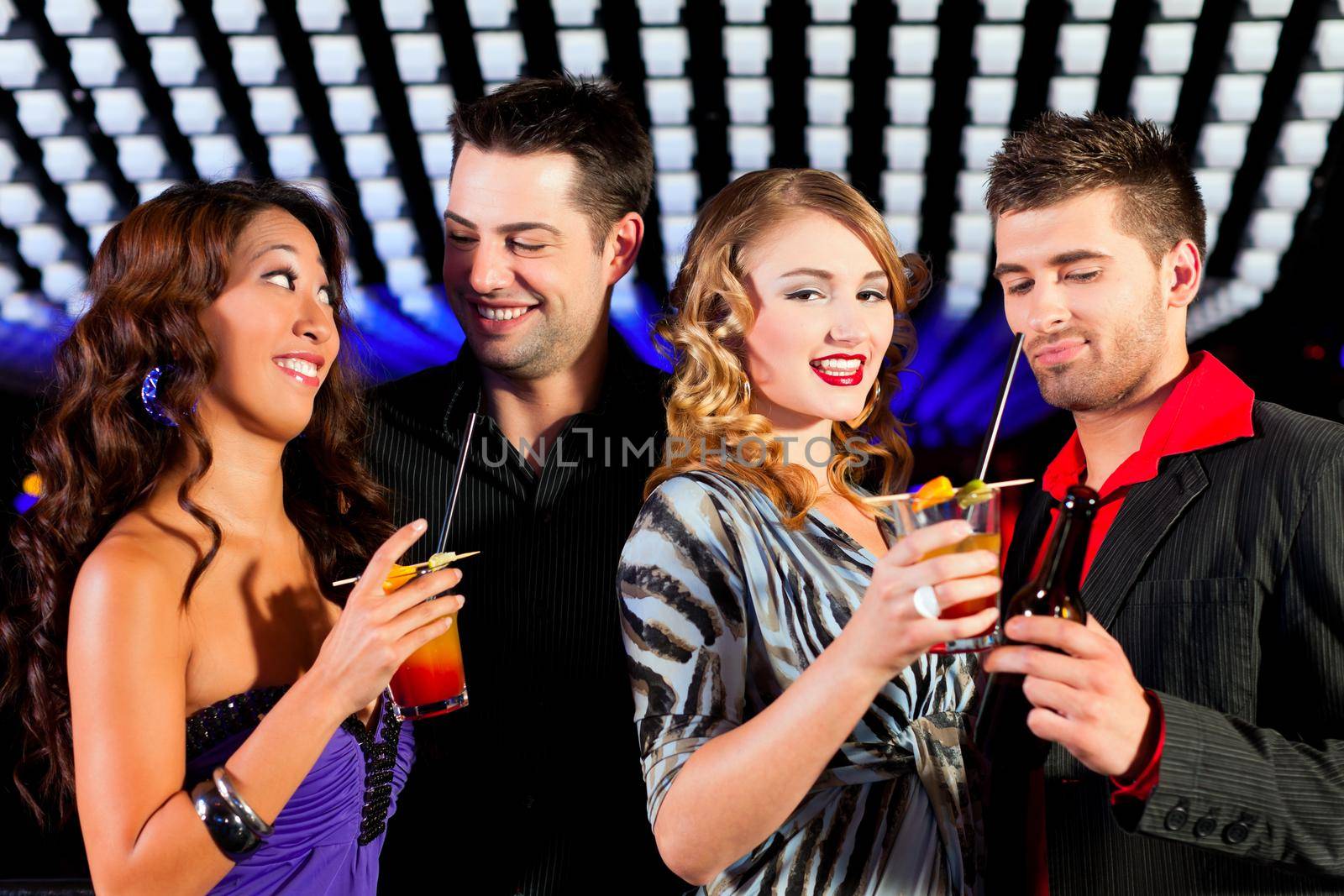 Group of party people with cocktails in a bar or club having fun