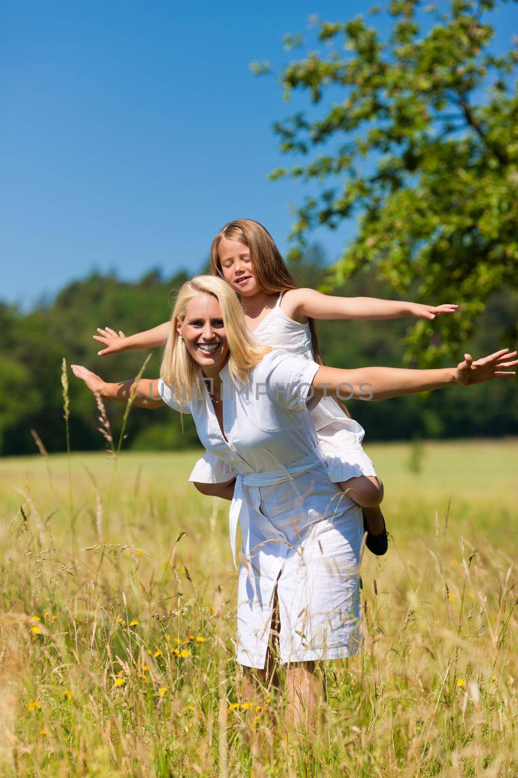 Mother is playing with daughter in meadow on a summer day