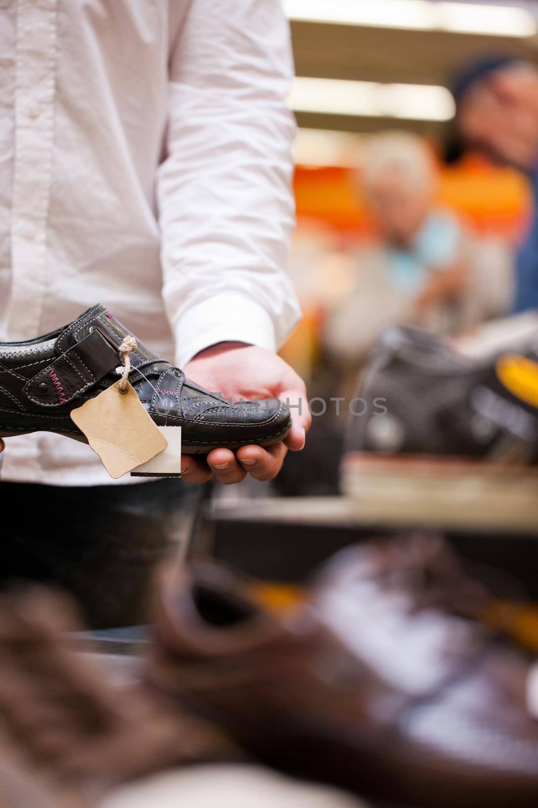 Male customer holding shoe with people in background