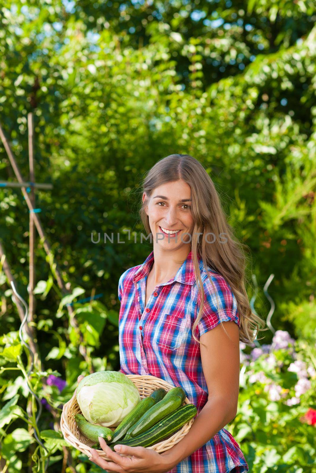 Gardening in summer - happy woman with freshly harvested vegetables