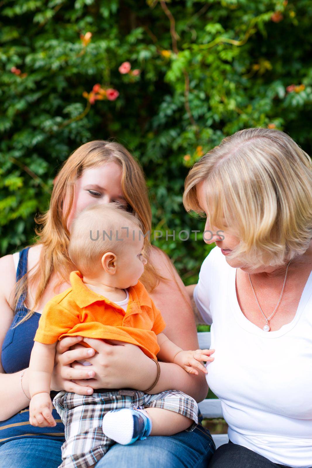 Family - Grandmother, mother and child sitting and playing in garden