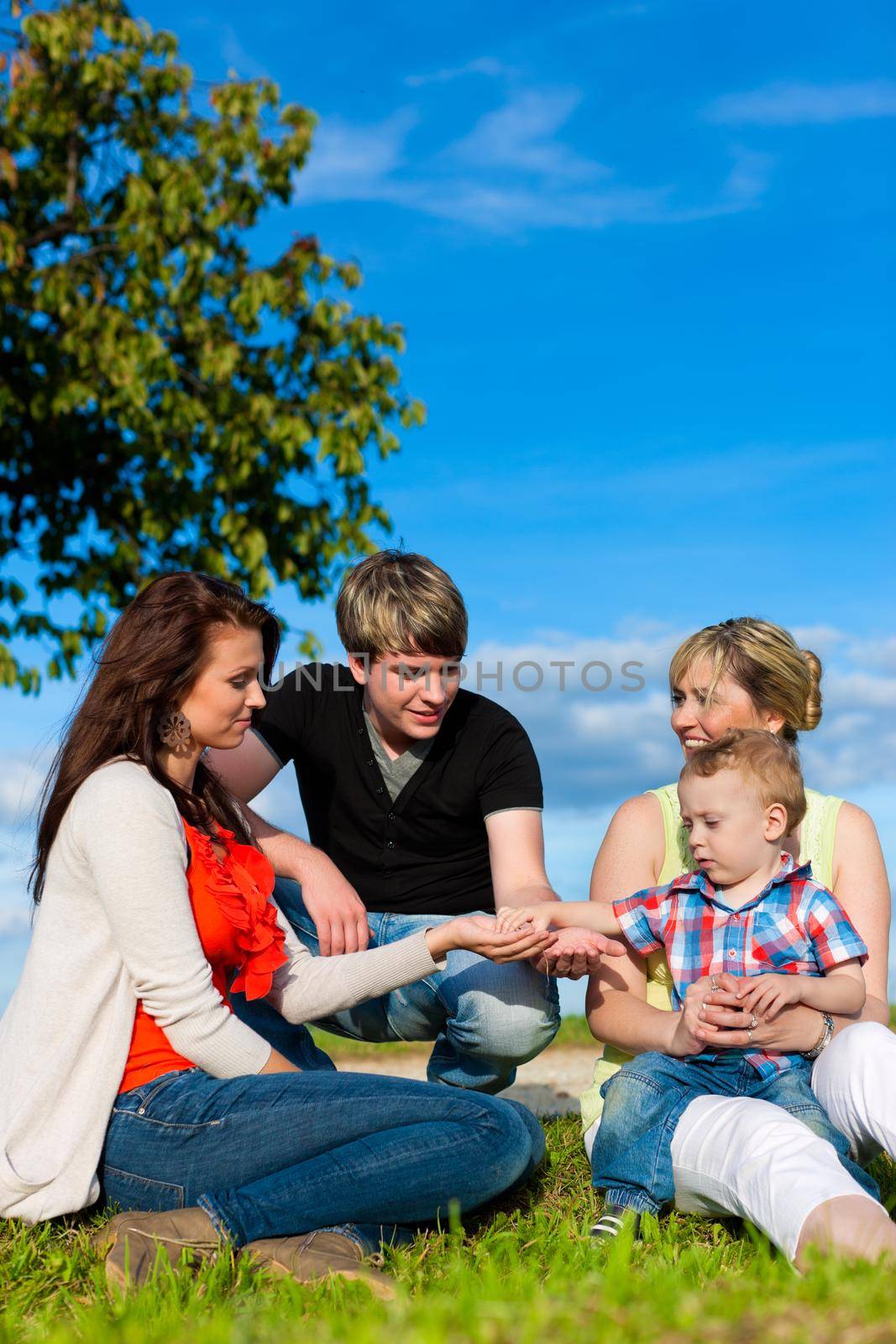 Family - Grandmother, mother, father and child sitting and playing in garden