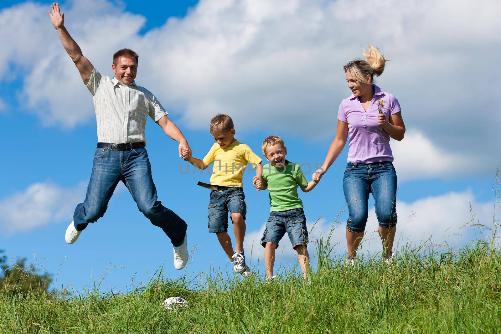 Happy family with children jumping in a meadow in summer