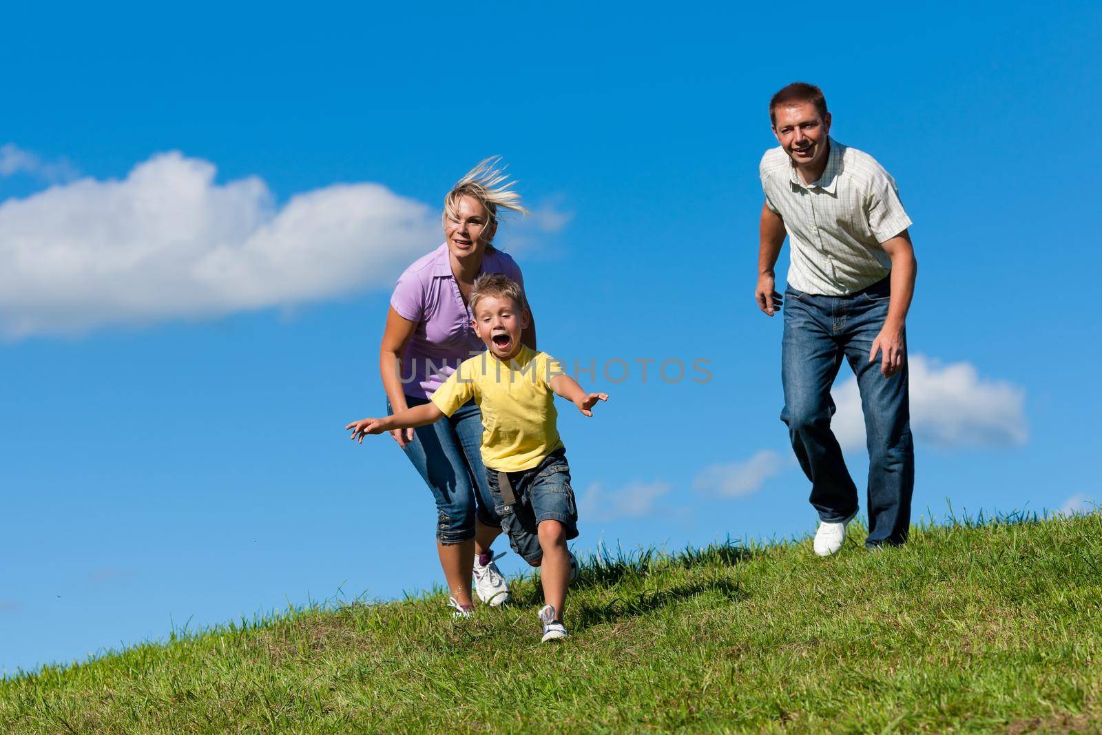 Family outdoors is running on a meadow by Kzenon