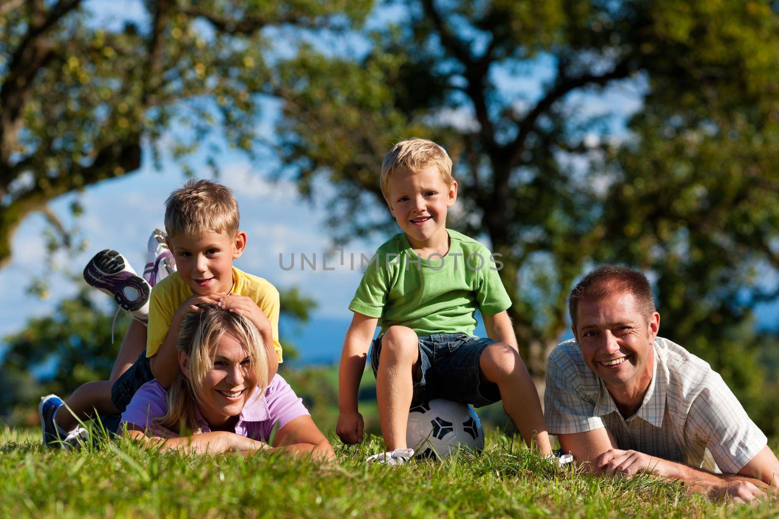 Family with children and football on a meadow by Kzenon