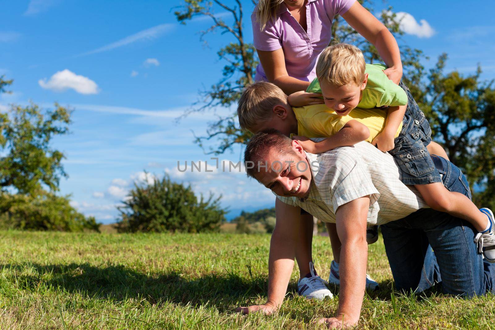 Family with children playing on a meadow by Kzenon