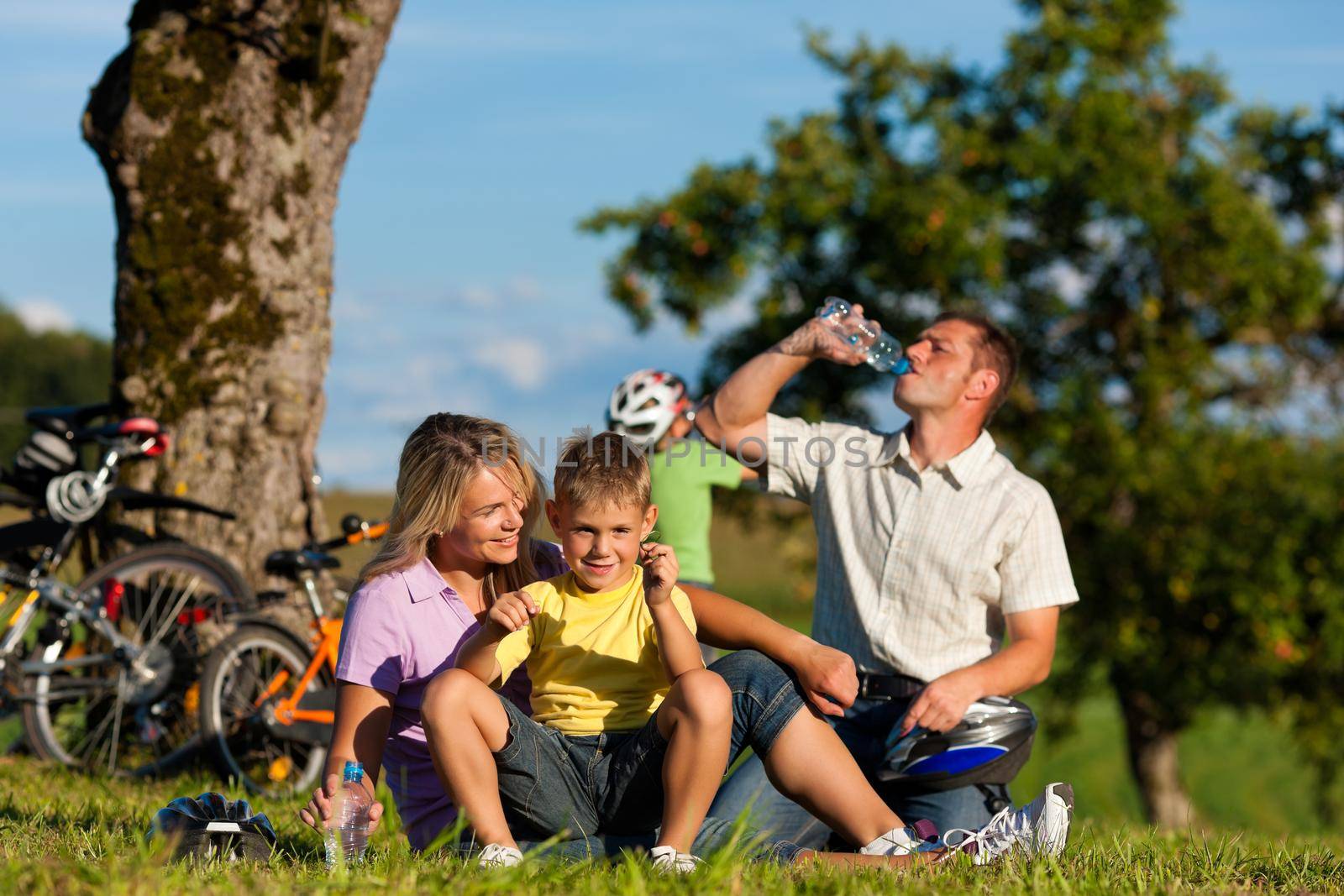 Happy family (father, mother and two sons) on getaway with bikes - they have a break