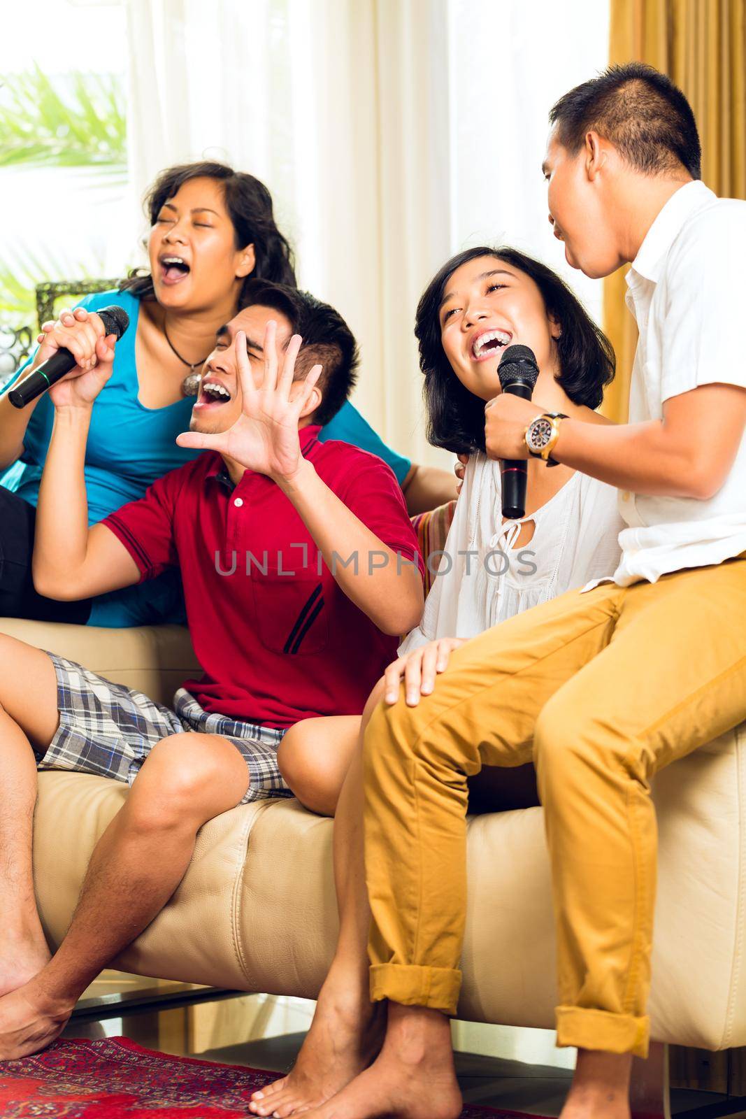 Asian people singing at karaoke party and having fun