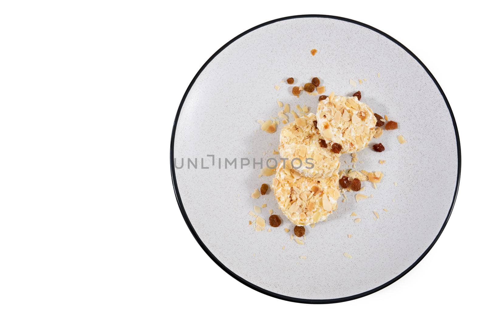 Top view of grey plate with appetizing dietary sweet cheesecakes sprinkled with raisins on white background. Concept of useful sweets without harm to the figure body. 