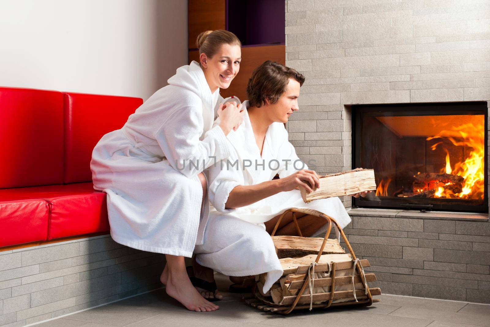 Young couple sitting in bathrobe for open fireplace, it is very romantic