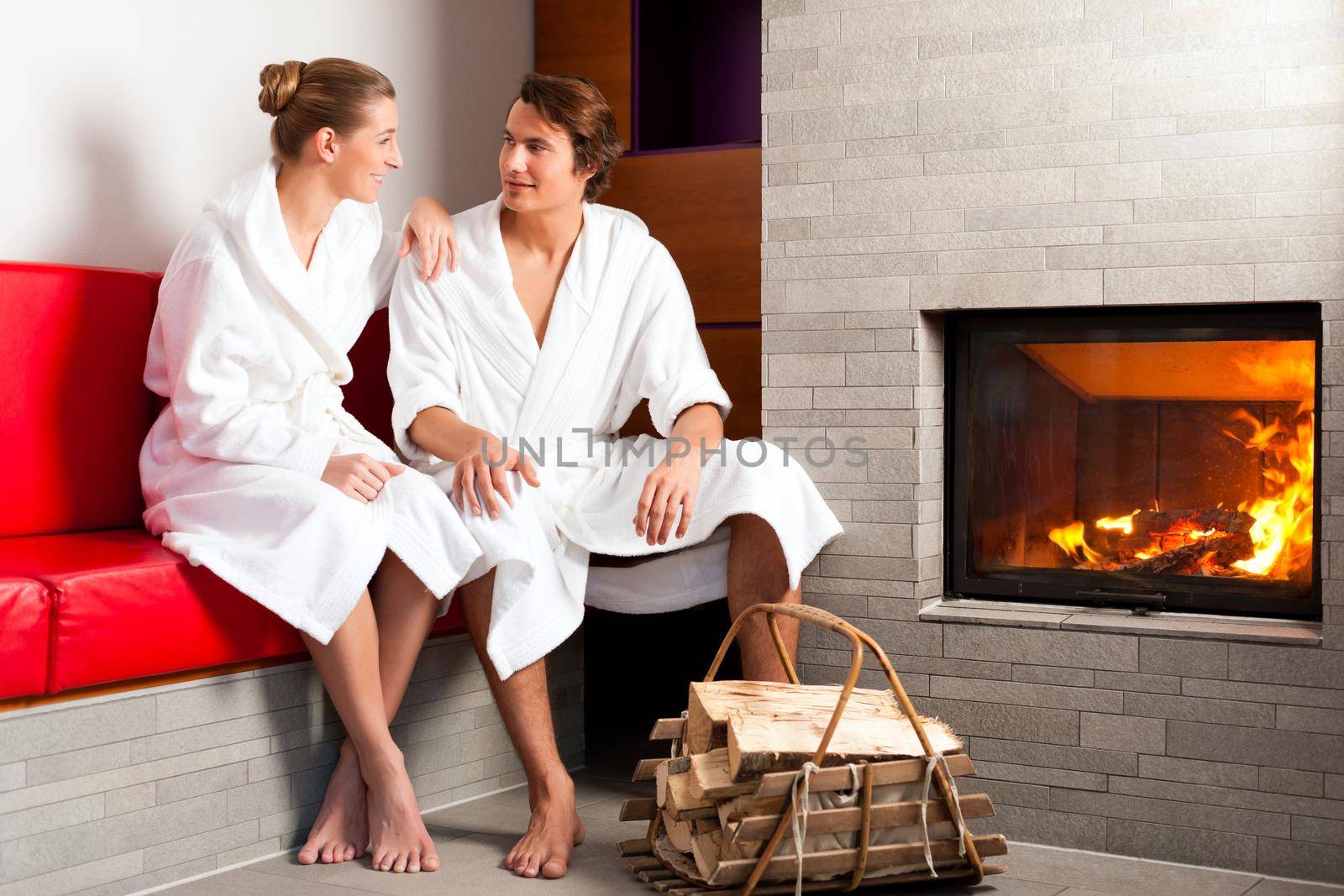 Young couple sitting in bathrobe for open fireplace, it is very romantic