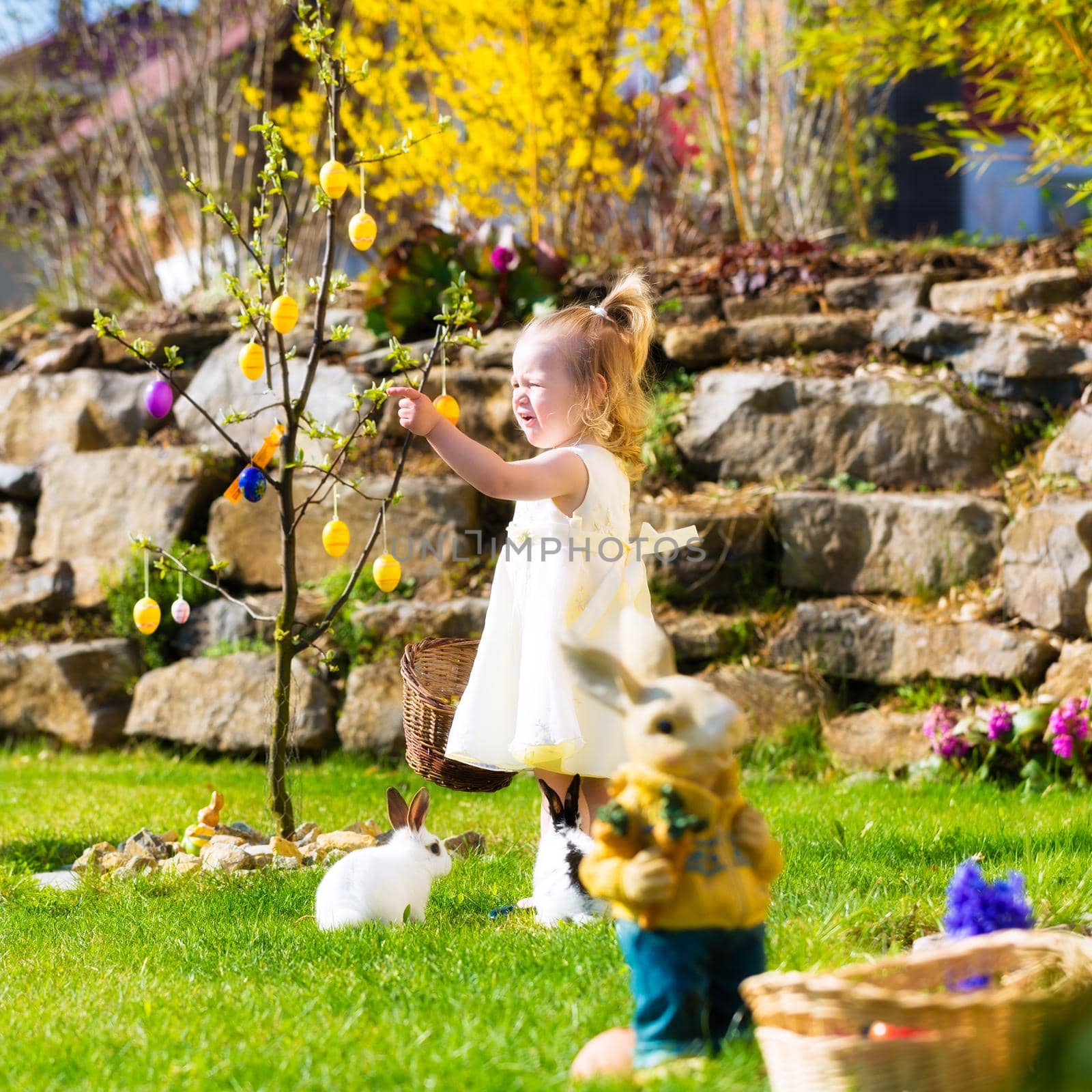 Little Girl on an Easter Egg hunt on a meadow in spring, she holding a basket or Easter basket