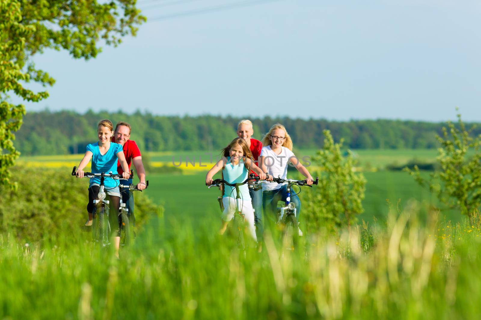 Family cycling outdoors in summer by Kzenon