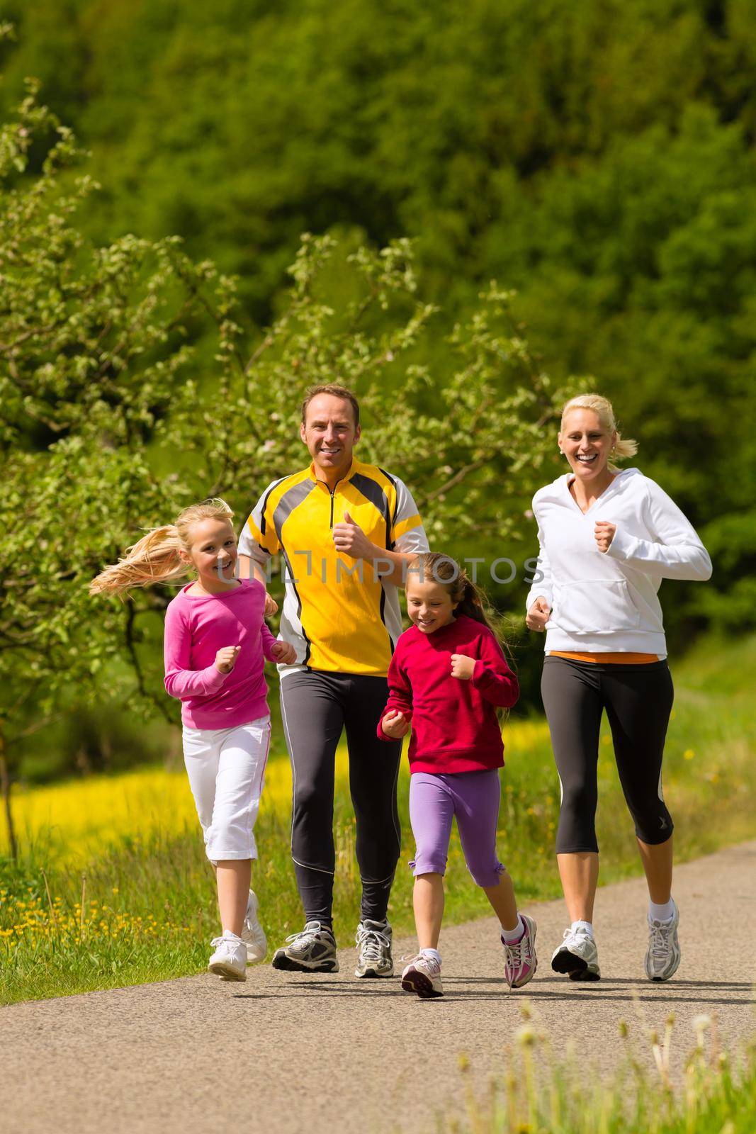 Family running in the meadow for sport by Kzenon