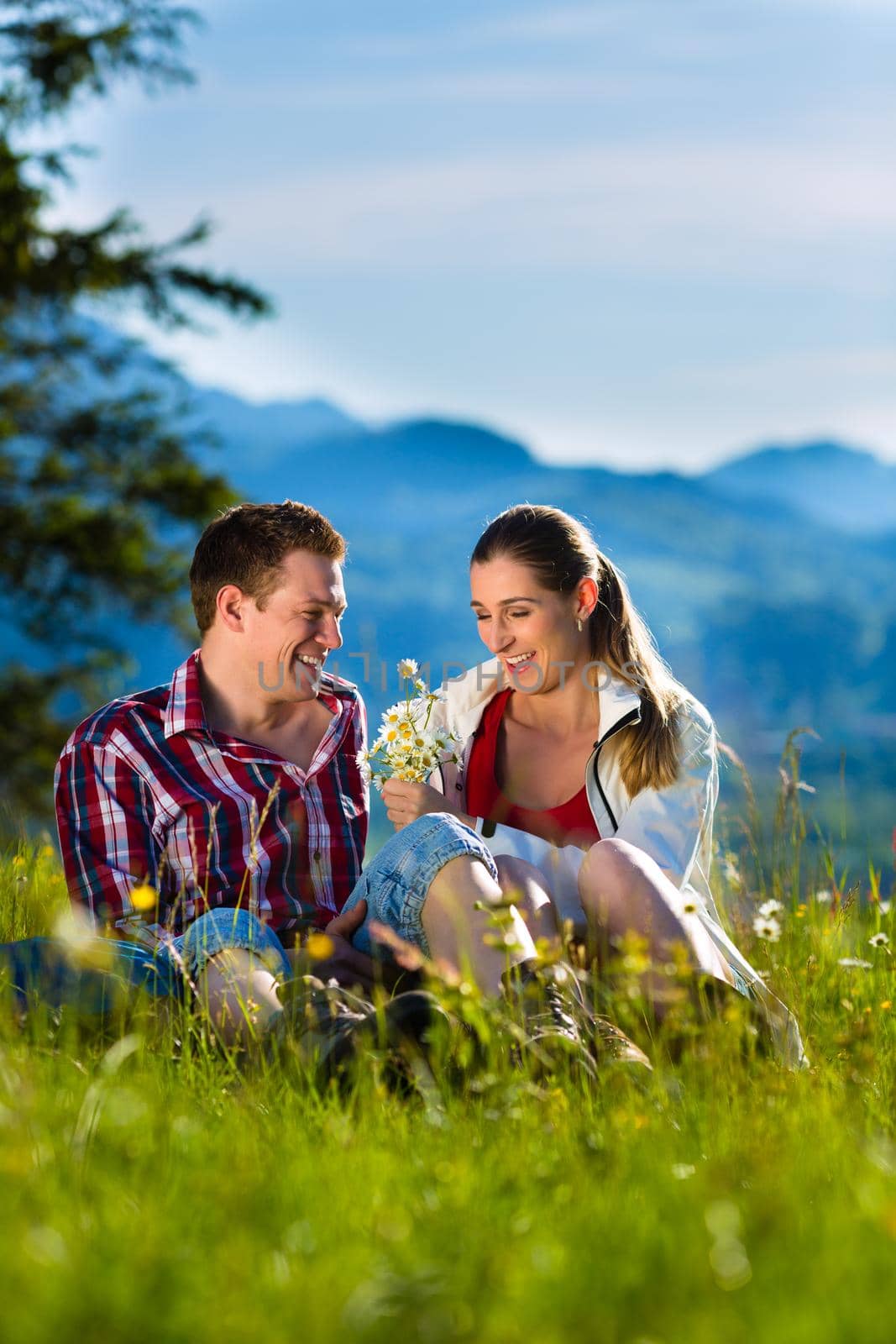 Couple is sitting in the meadow with mountain by Kzenon