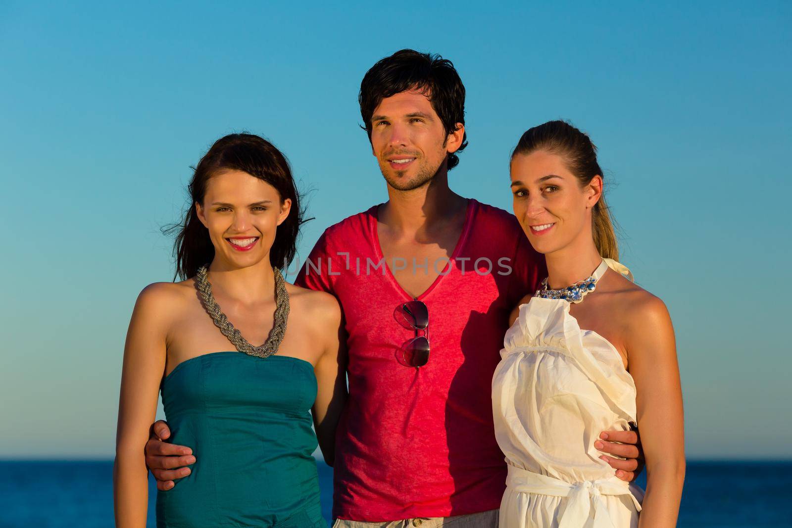 Man and two women enjoy the romantic sunset