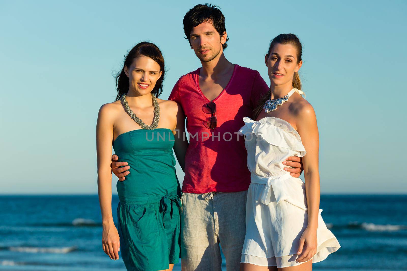 Man and two women enjoy the romantic sunset
