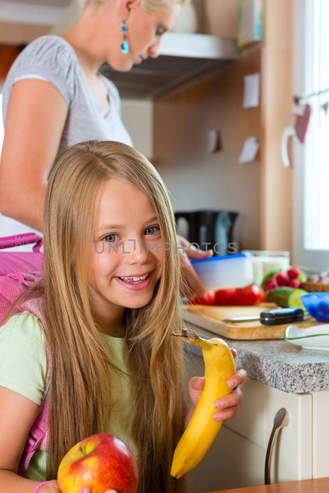 Family - mother making breakfast for her children in the morning and a snack for school