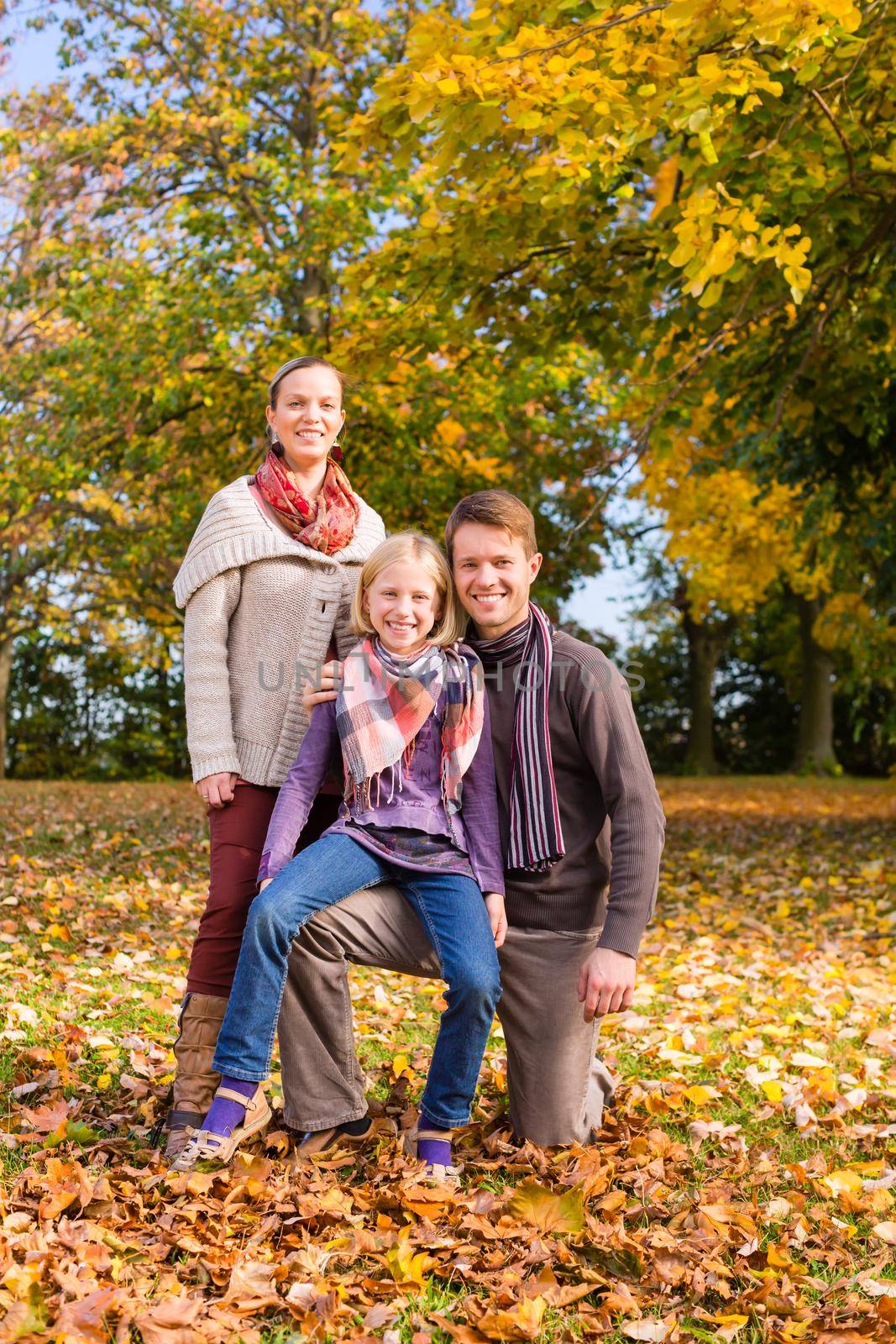 Family in front of colorful trees in autumn or fall by Kzenon