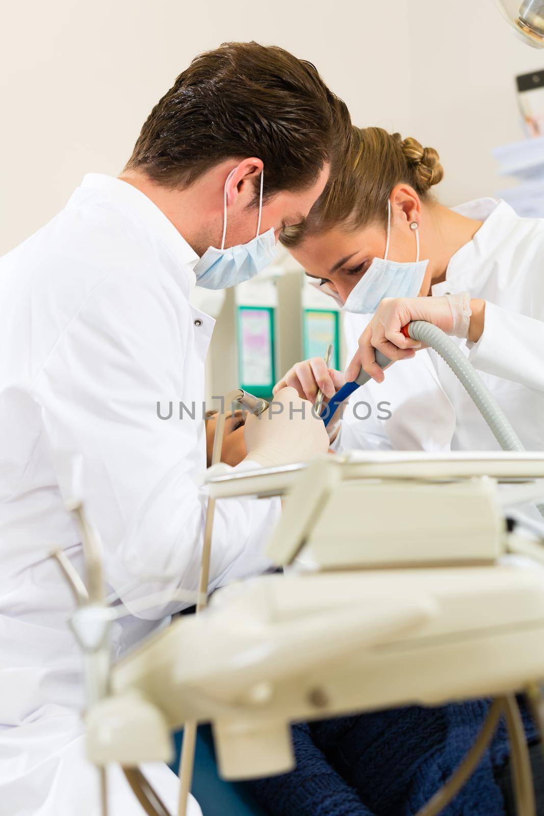 Female patient with dentist and assistant in a dental treatment, wearing masks and gloves