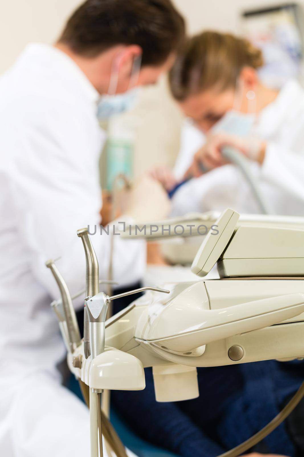 Female patient with dentist and assistant in a dental treatment, wearing masks and gloves