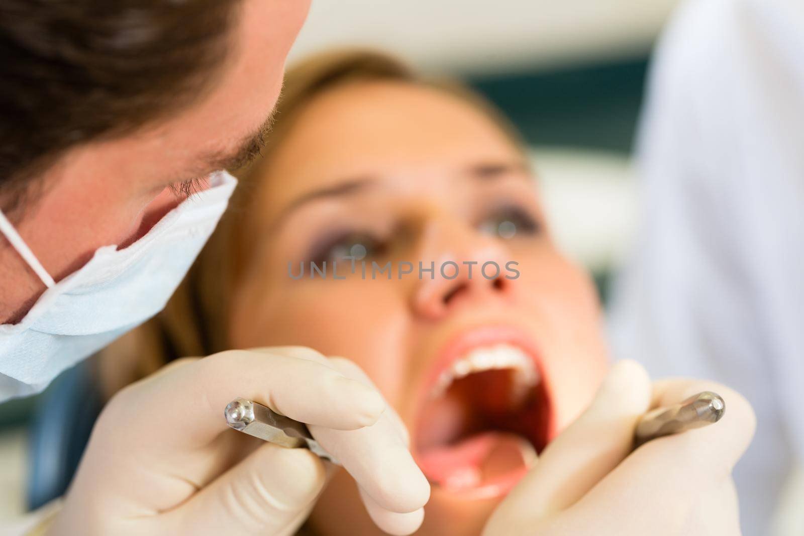 Female patient with dentist in a dental treatment, wearing masks and gloves