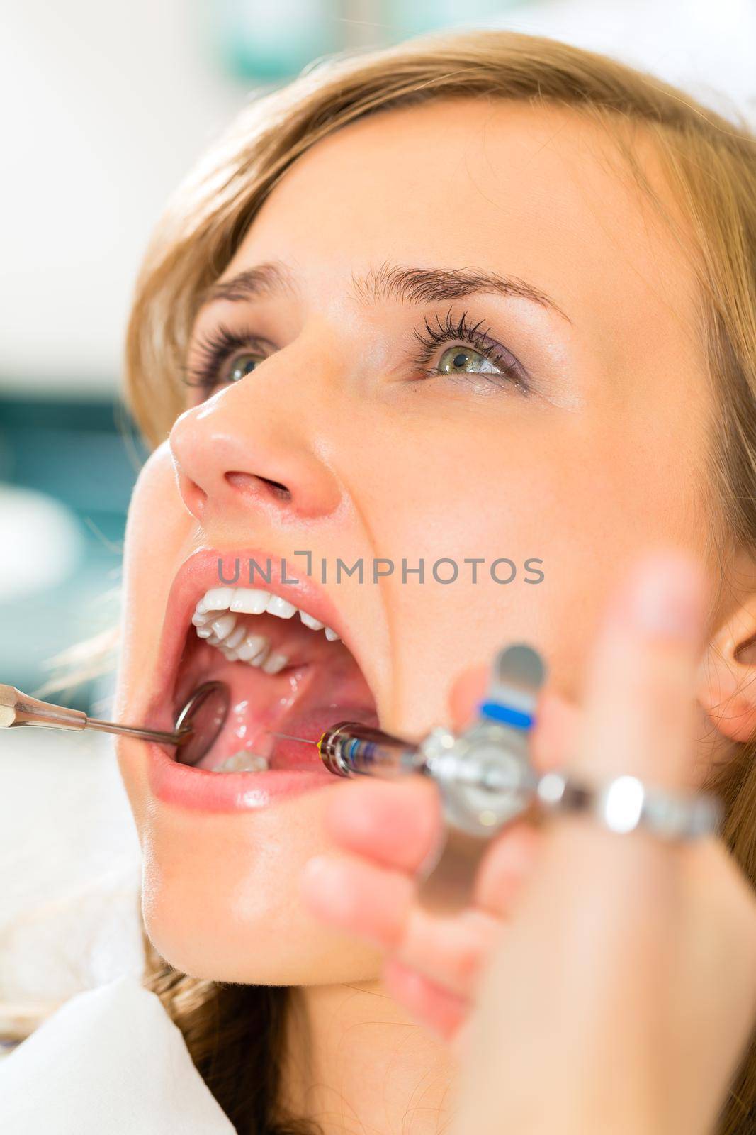 dentist holding a syringe and anesthetizing his patient