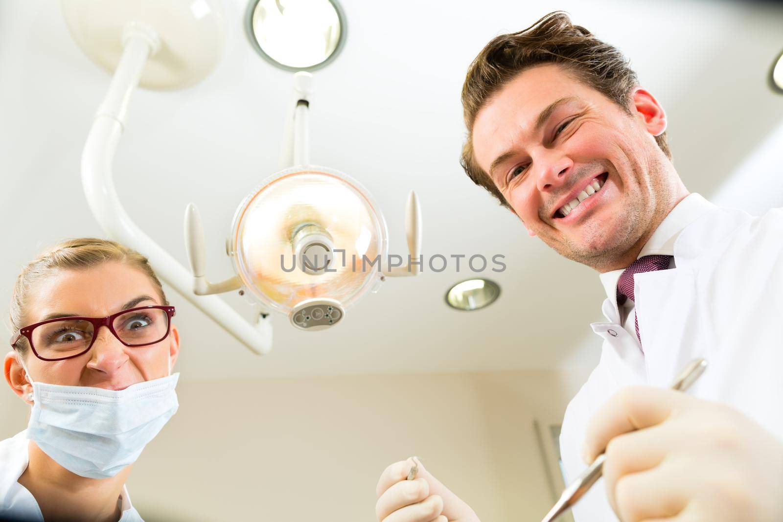 Scary dentist and assistant at a treatment, from the perspective of a patient