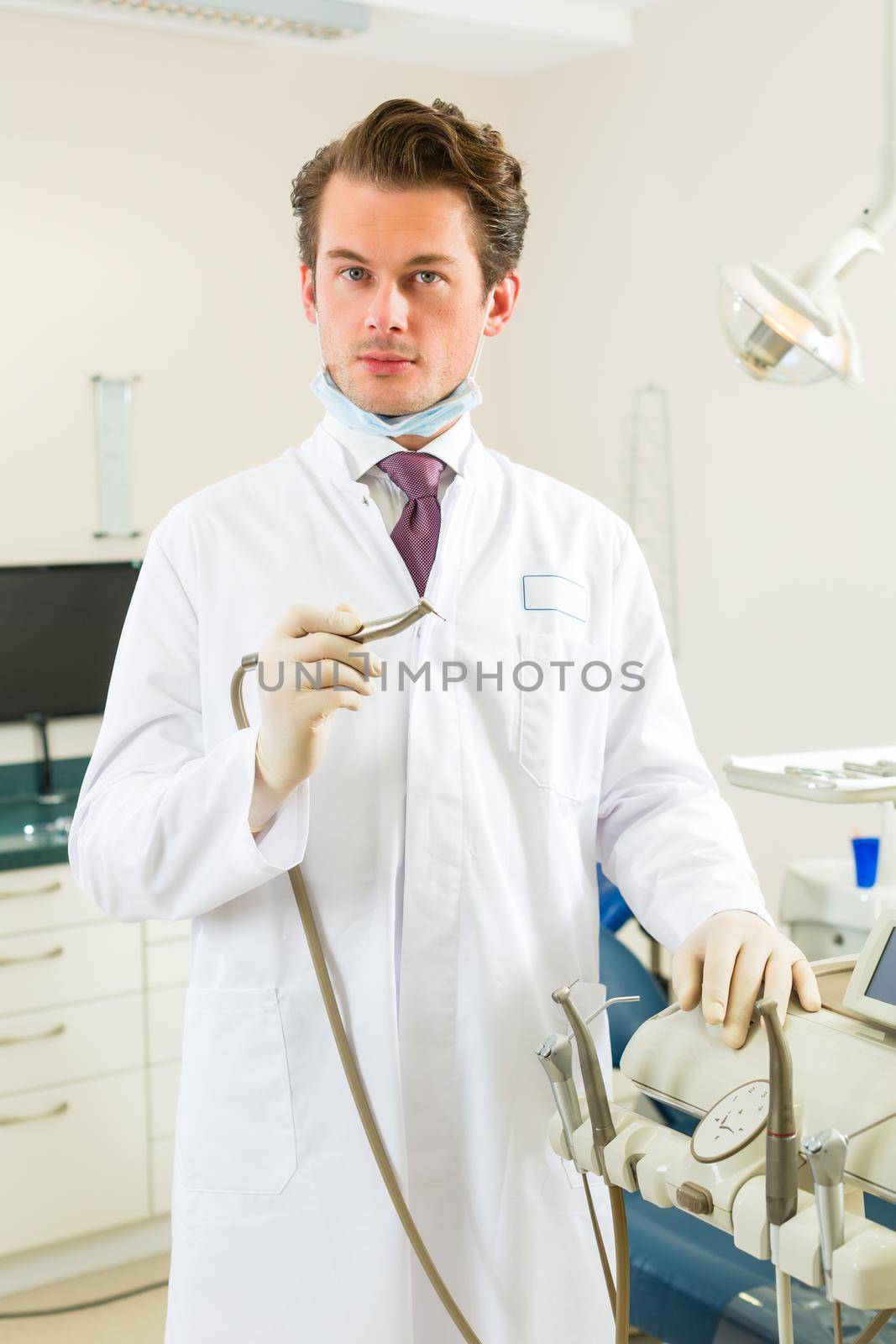 Dentist in his surgery, he holds a drill by Kzenon