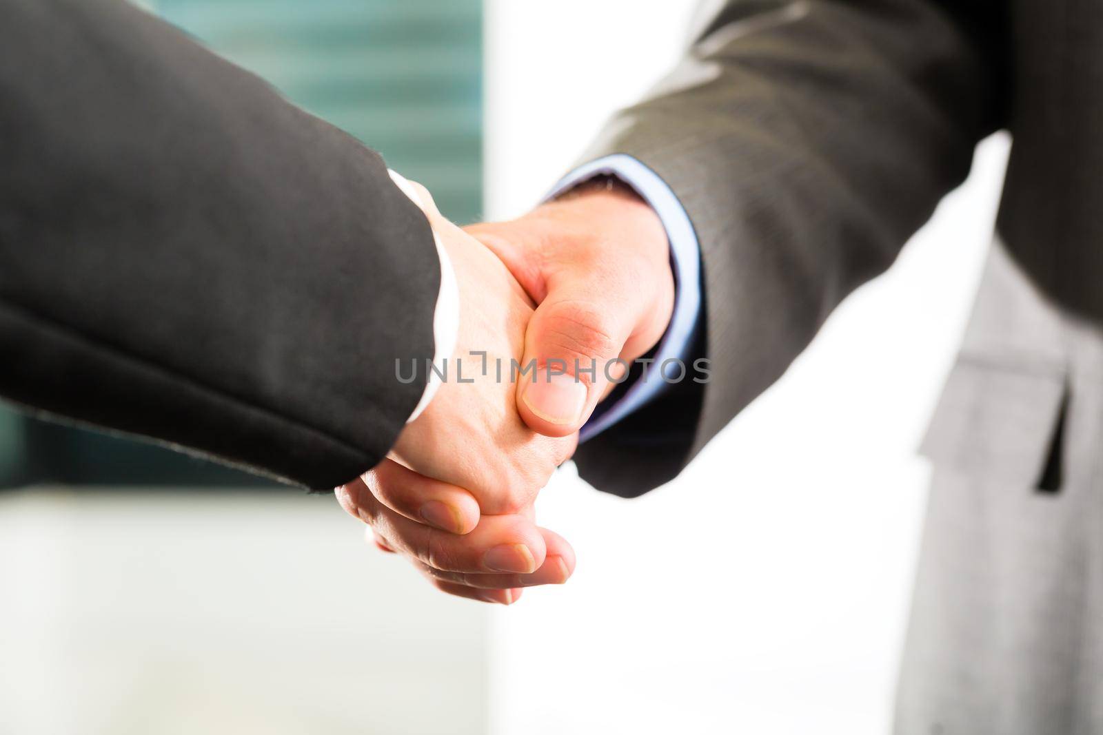 Two businessperson shaking hands closing a deal, closeup