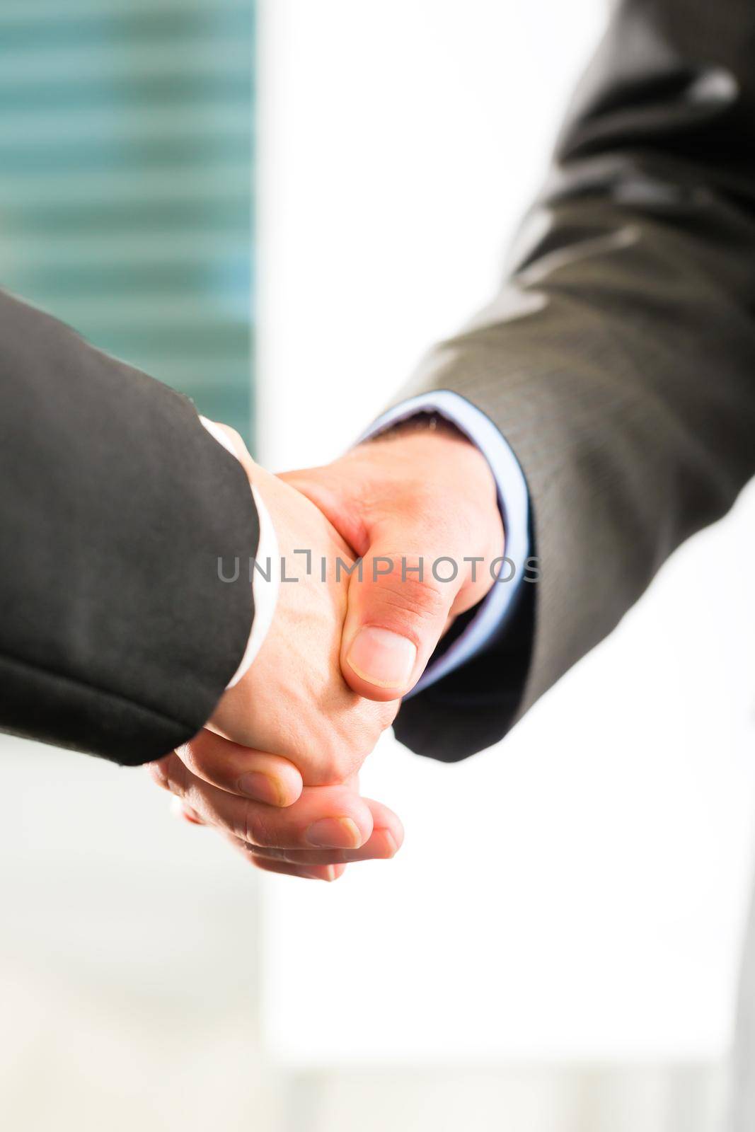Two businessperson shaking hands closing a deal, closeup