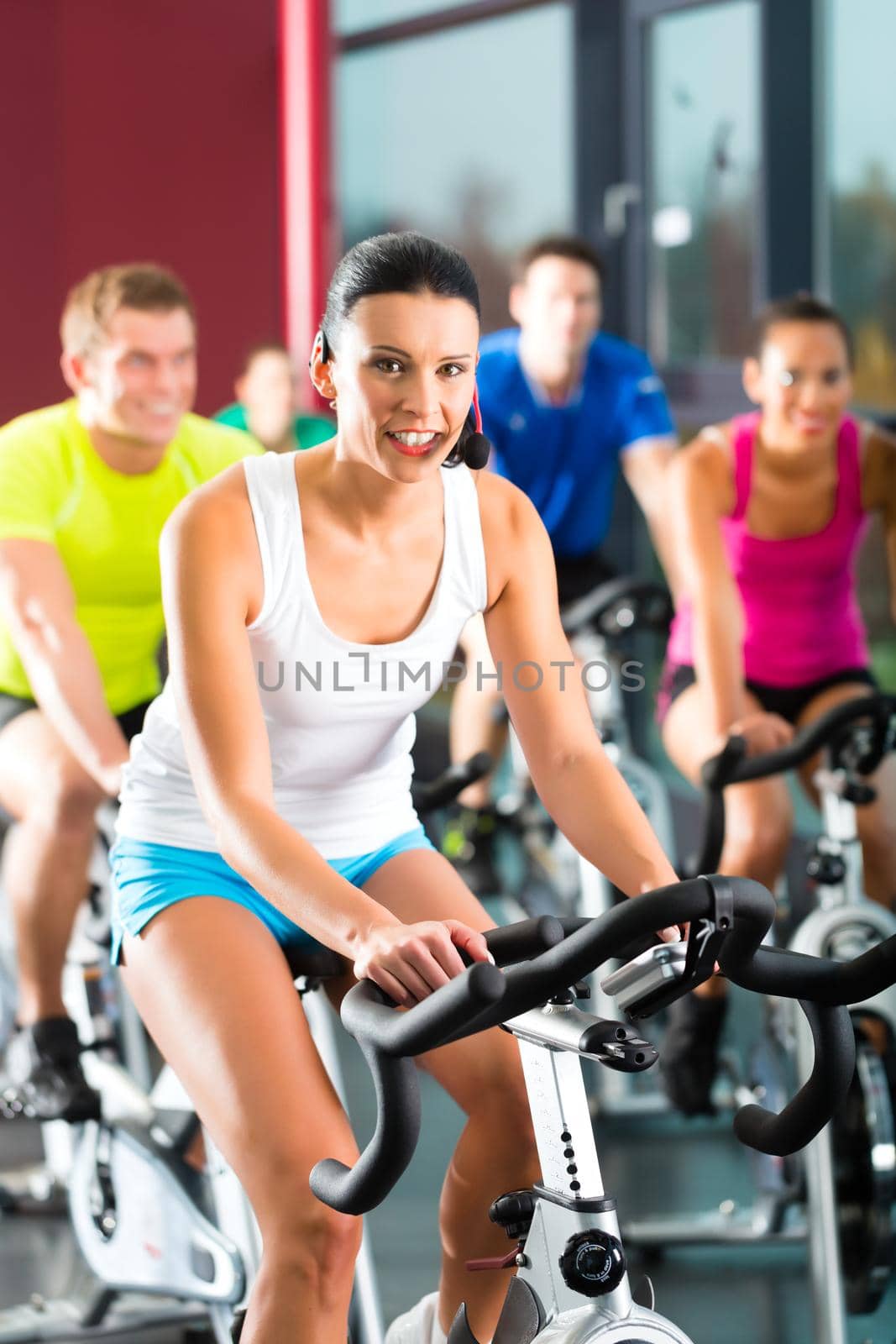 Young People - group of women and men - doing sport Spinning in the gym for fitness