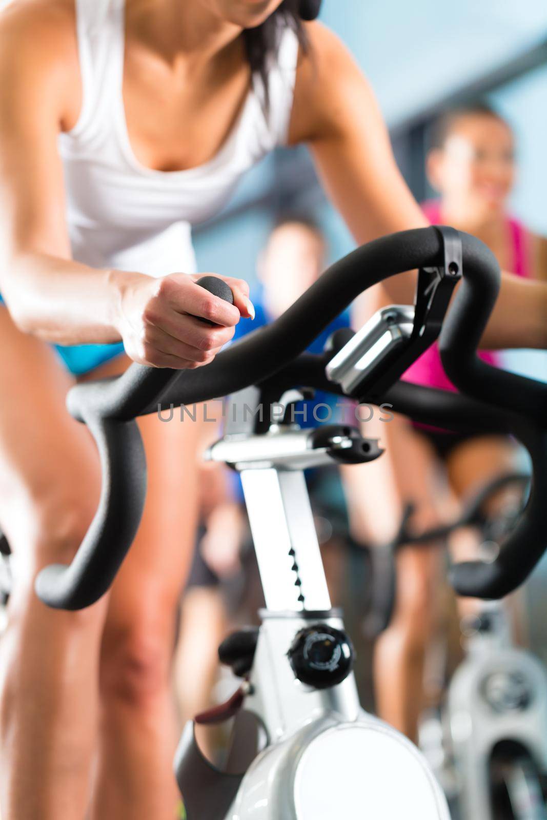 Young People - group of women and men - doing sport Spinning in the gym for fitness