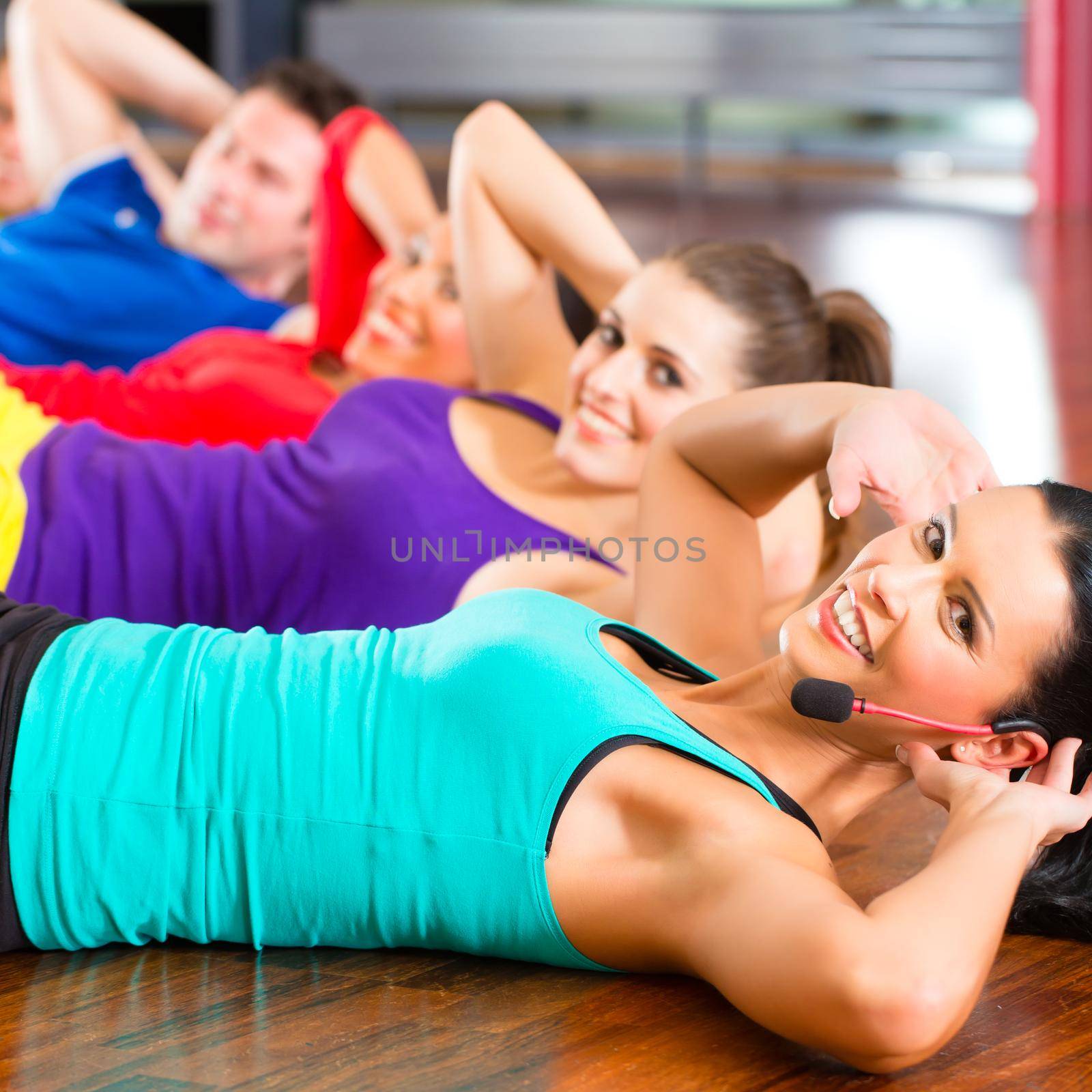 Fitness group with instructor in gym doing stomach crunches for sport