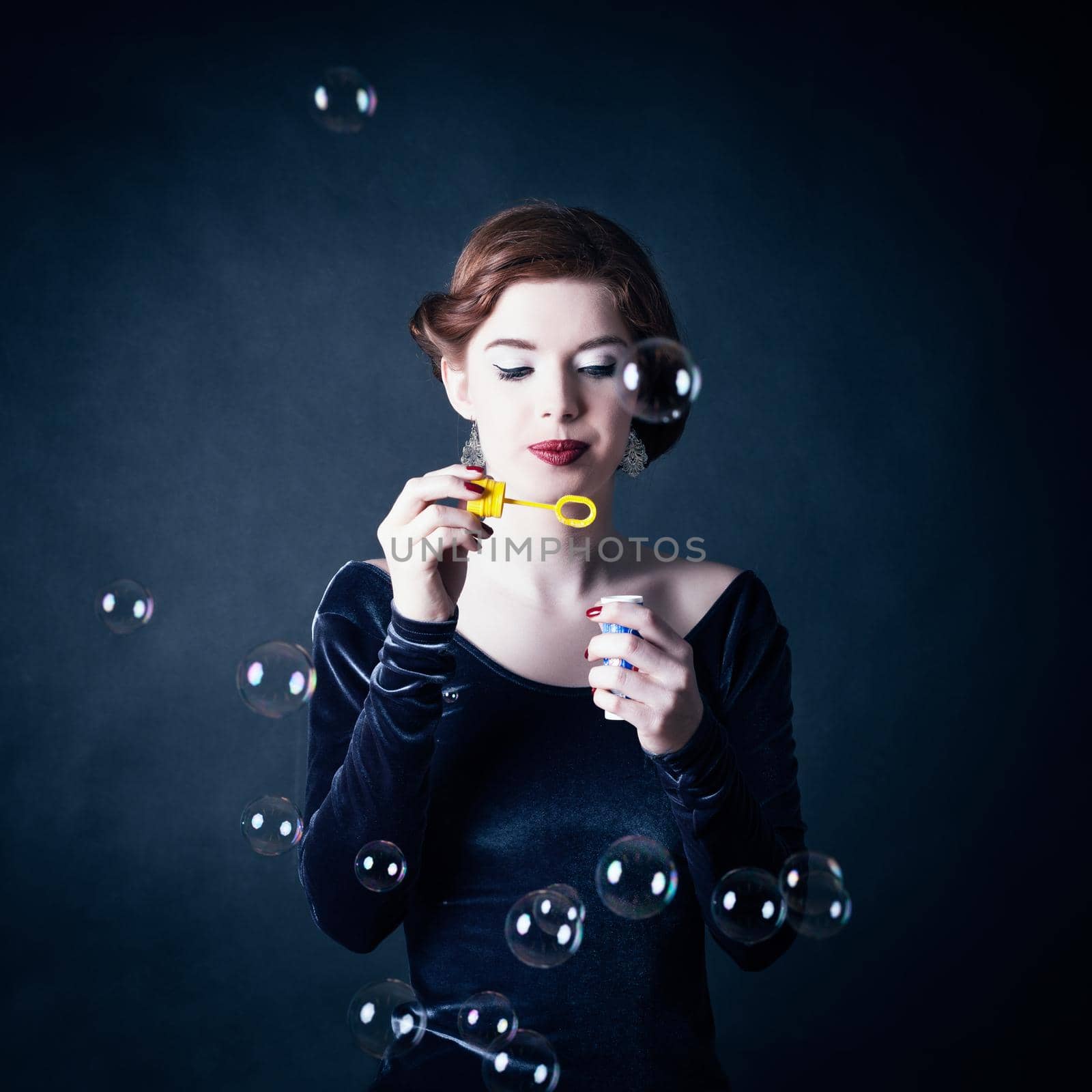 Girl making soap bubbles in front of dark background