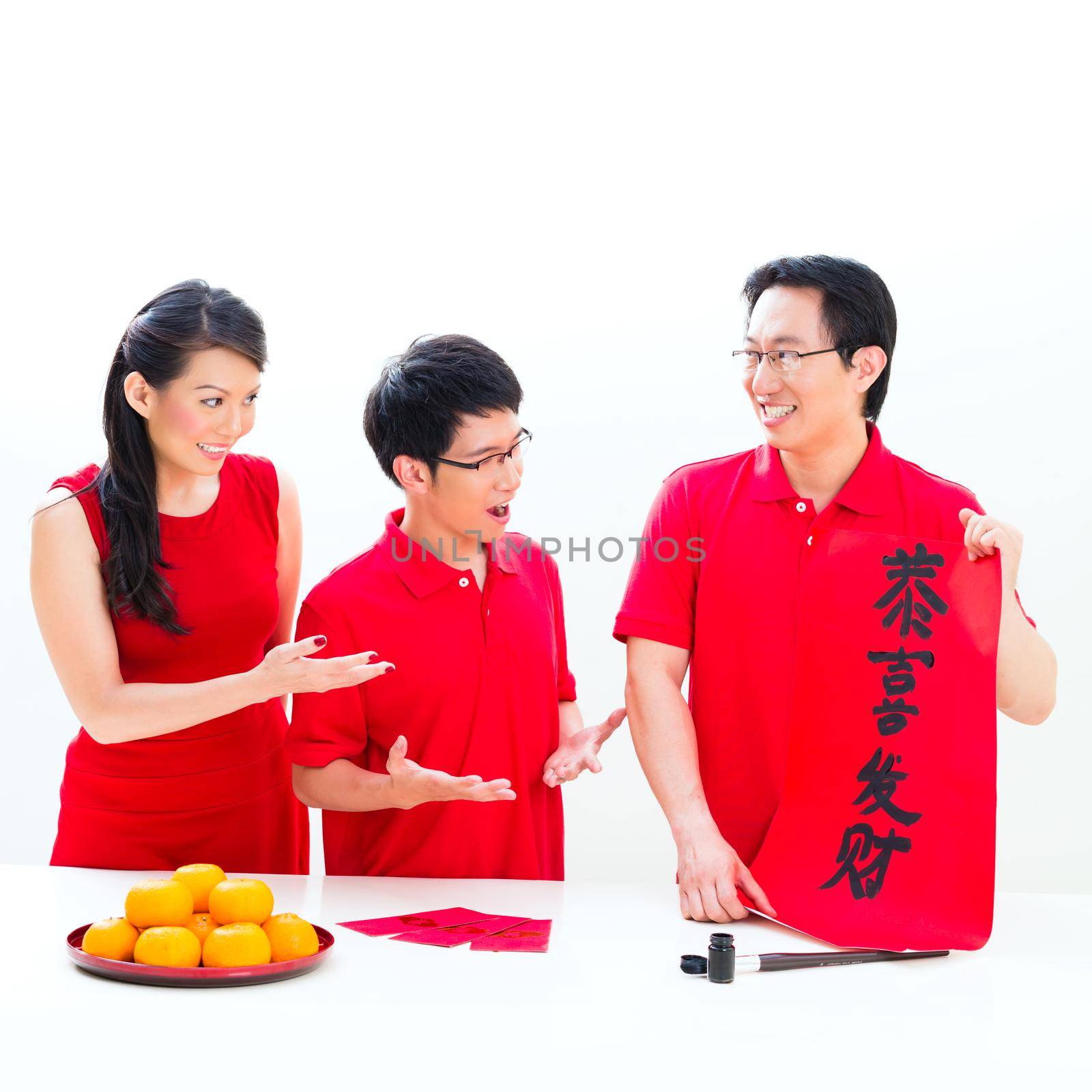 Friends family celebrate Chinese new year with traditional calligraphy, wearing red shirts