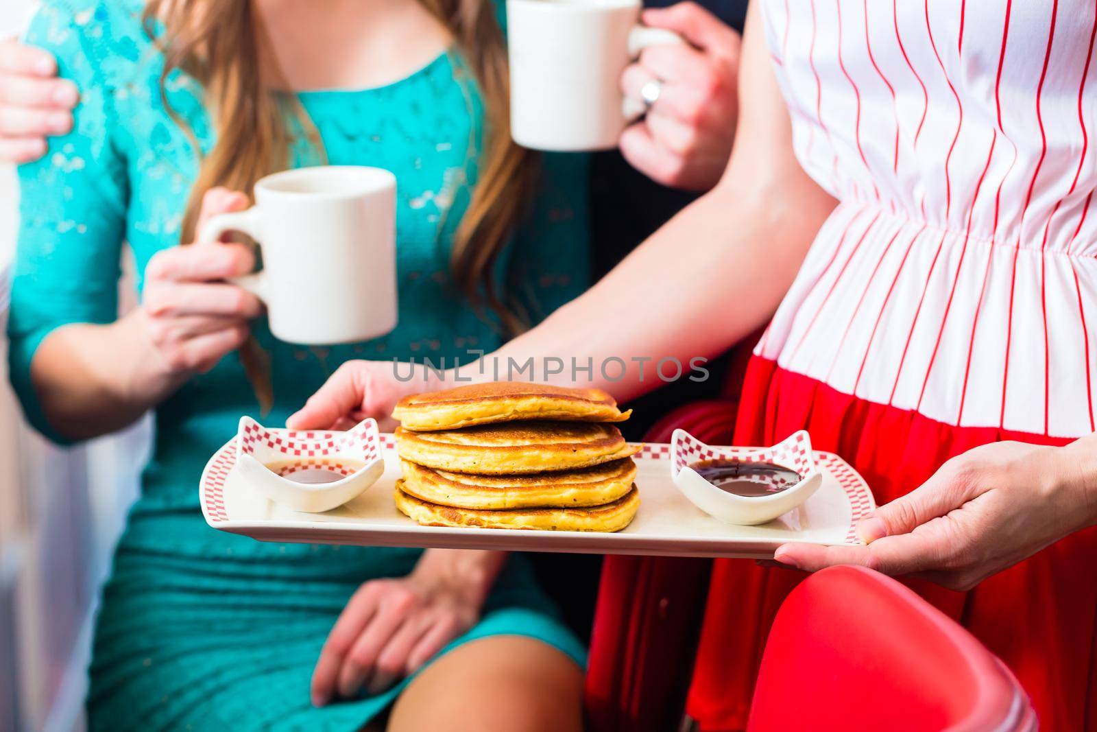 People in diner or restaurant having pancakes by Kzenon