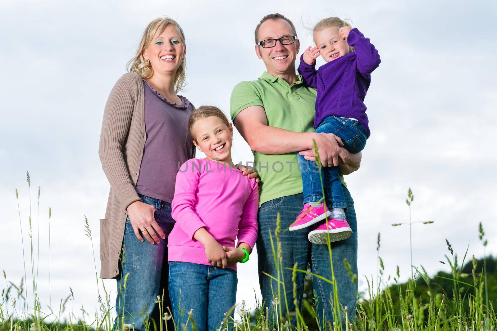 Mother, father and kids or daughter and friend standing outdoor on grass meadow