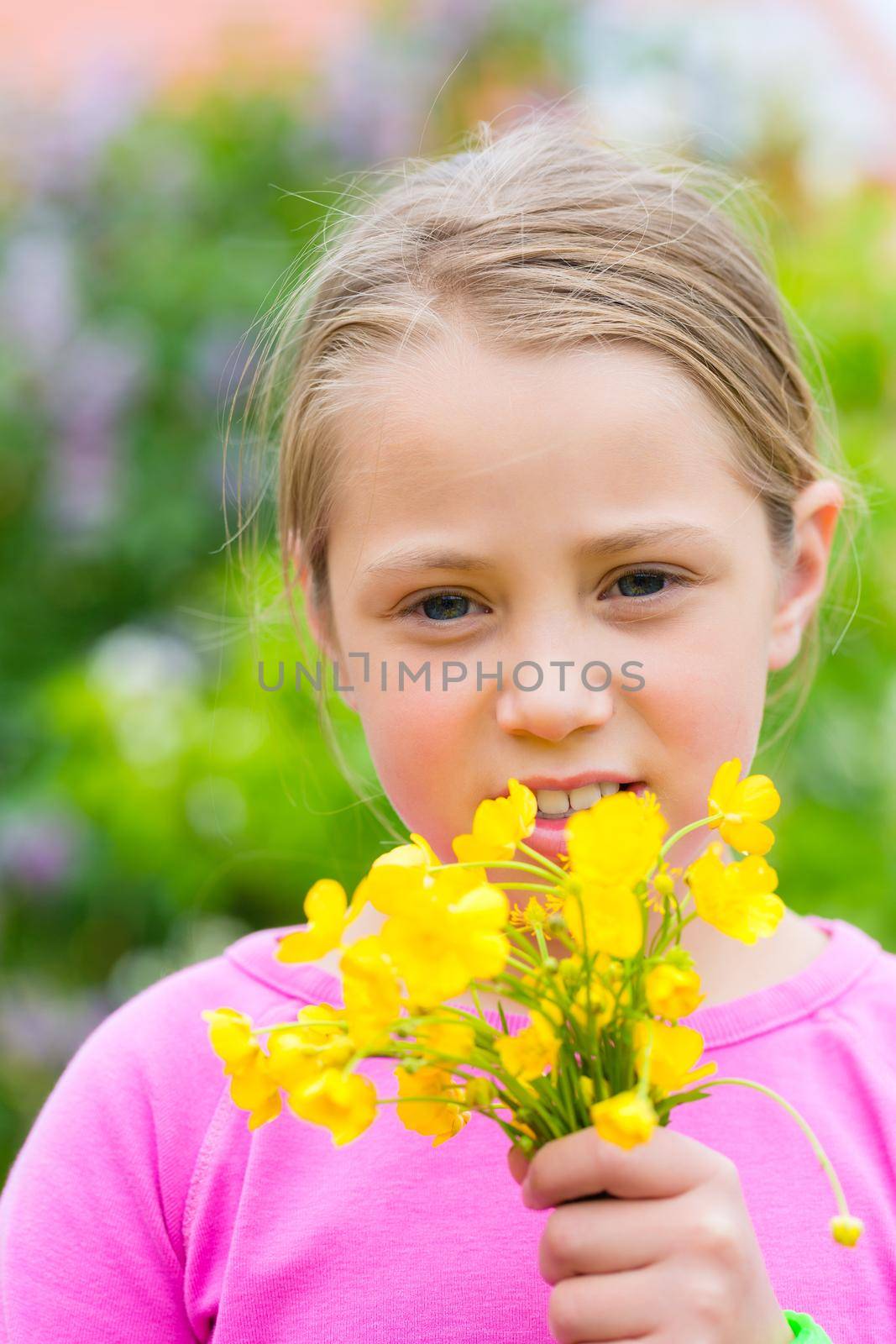 Girl holding outdoor on grassland a bouquet of buttercups in her hand