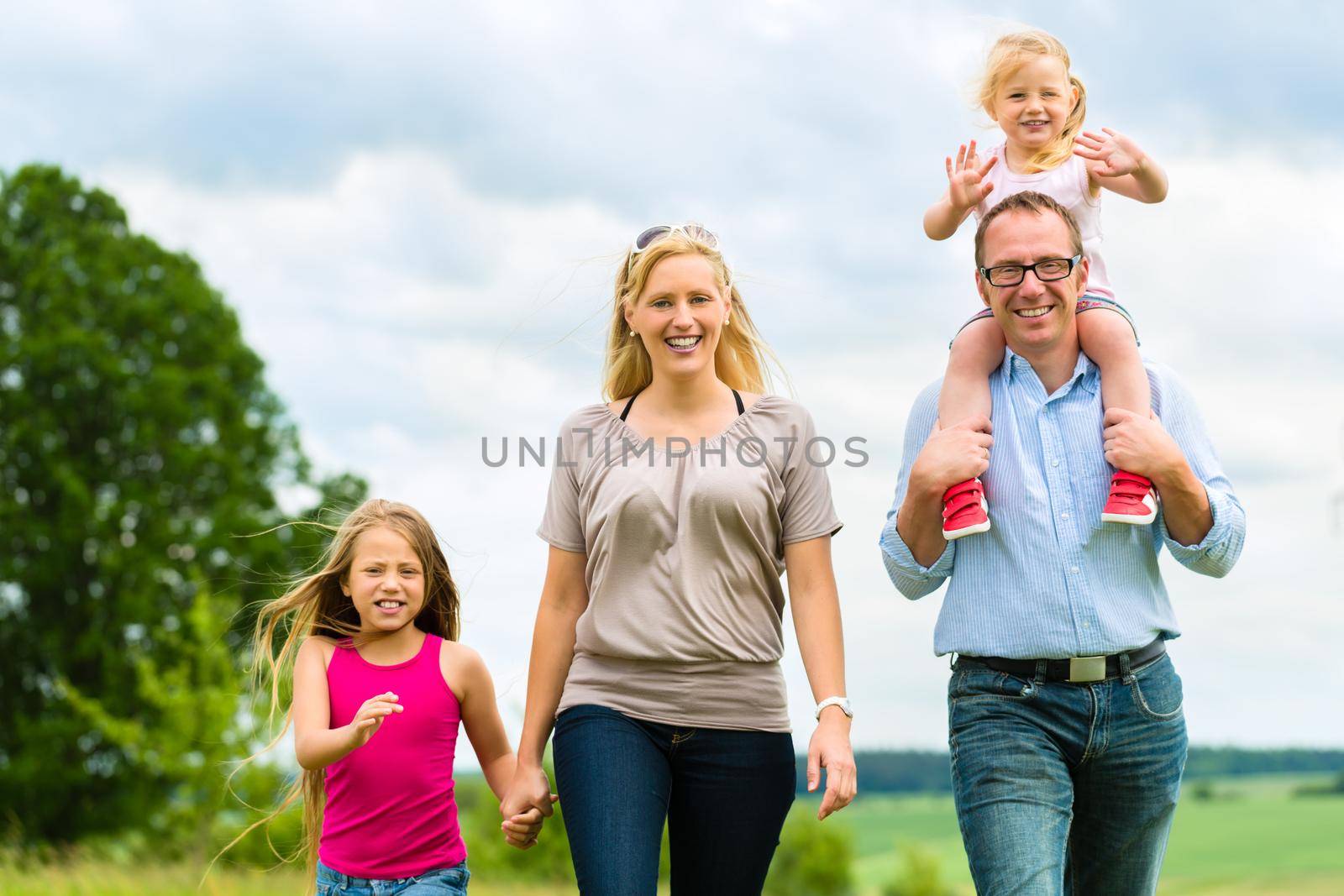 Happy Family with girls or daughters walking in a meadow in summer