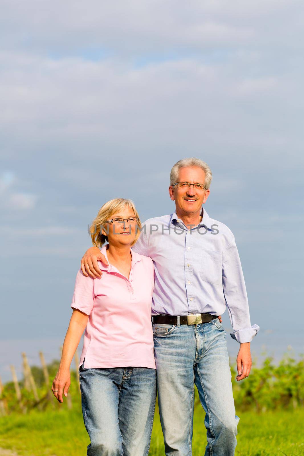 Man and woman, senior couple, having a walk in summer or outdoors in the vineyard