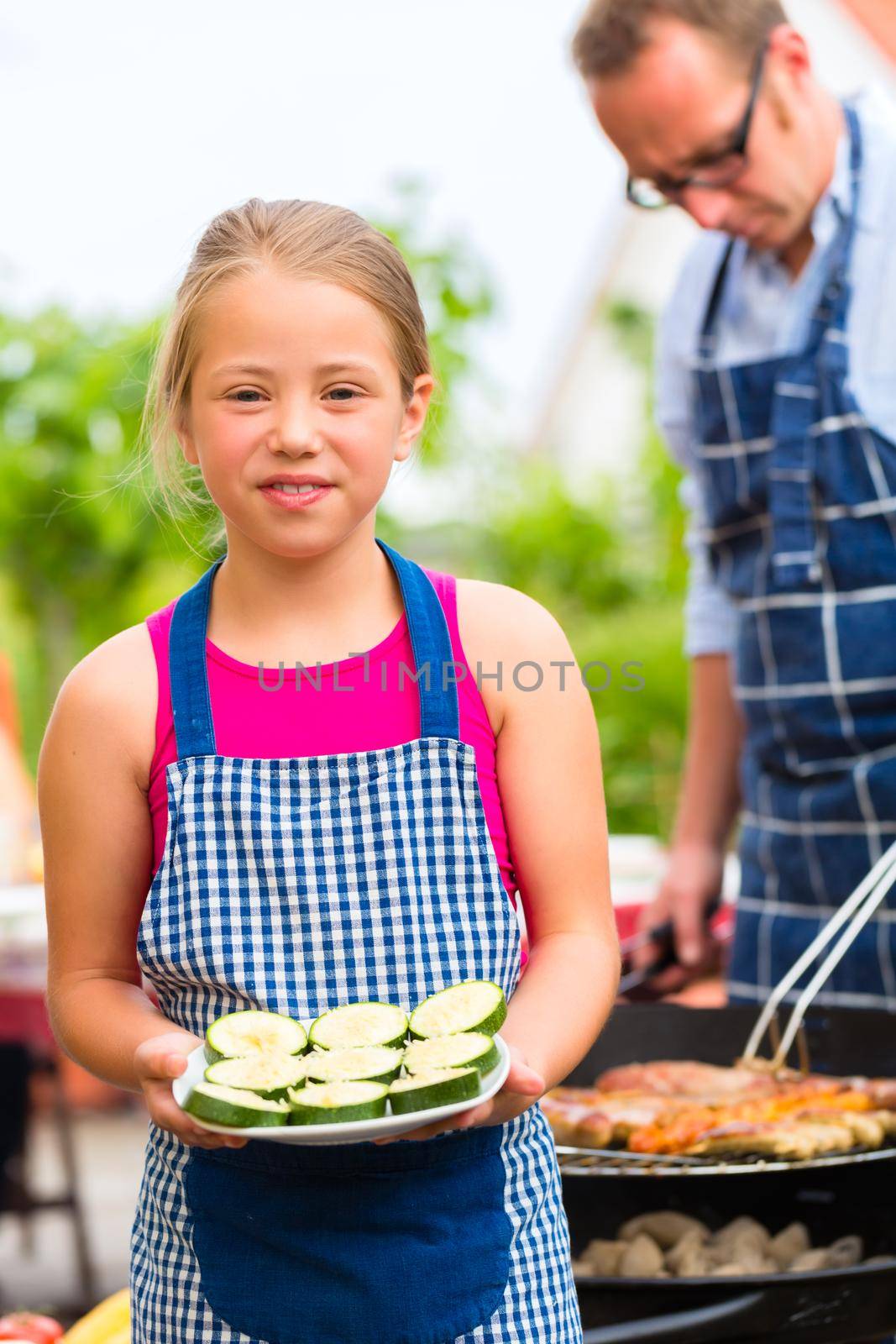 Father and daughter making barbecue in the garden in summer with sausages and meat