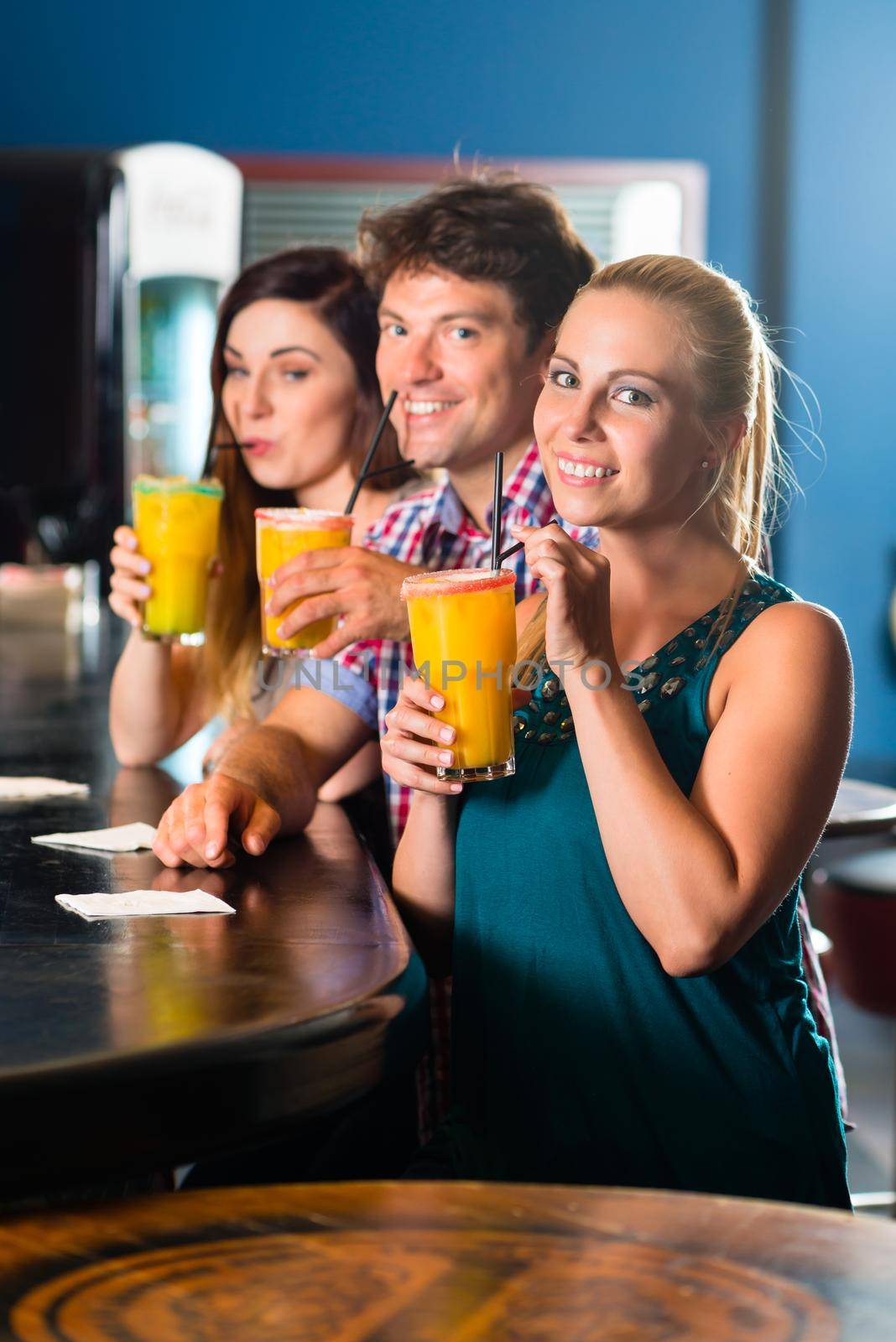 Young people in club or bar drinking cocktails and having fun