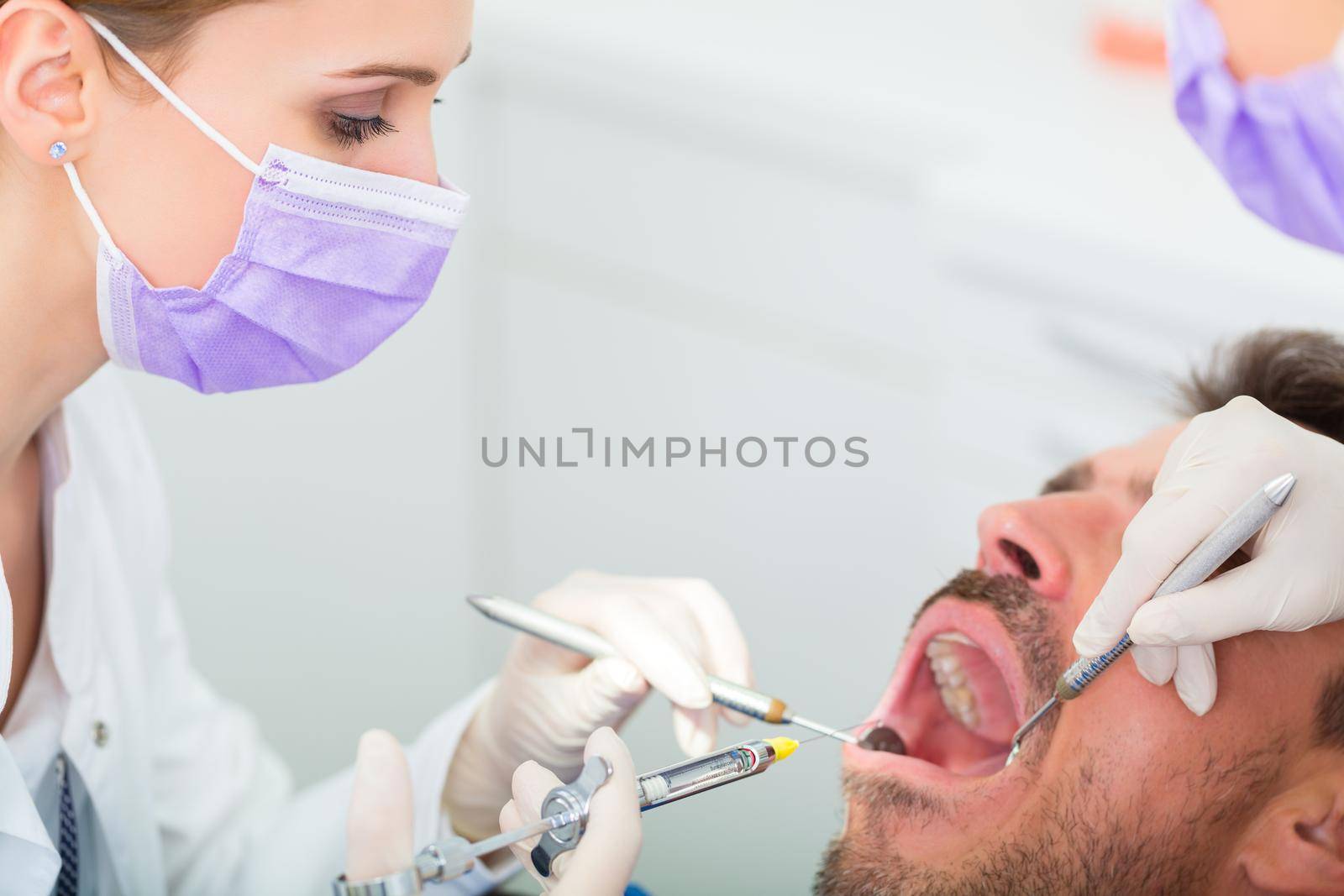 Dentist giving treatment - anesthetization syringe by Kzenon