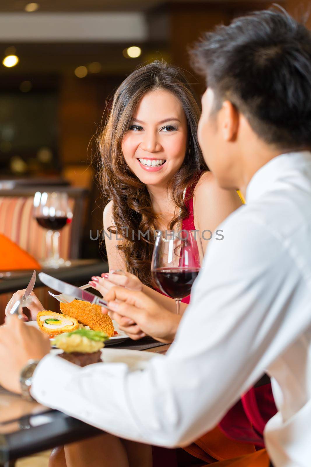 Asian Chinese couple - Man and woman - or lovers flirting and having a date or romantic dinner in a fancy restaurant